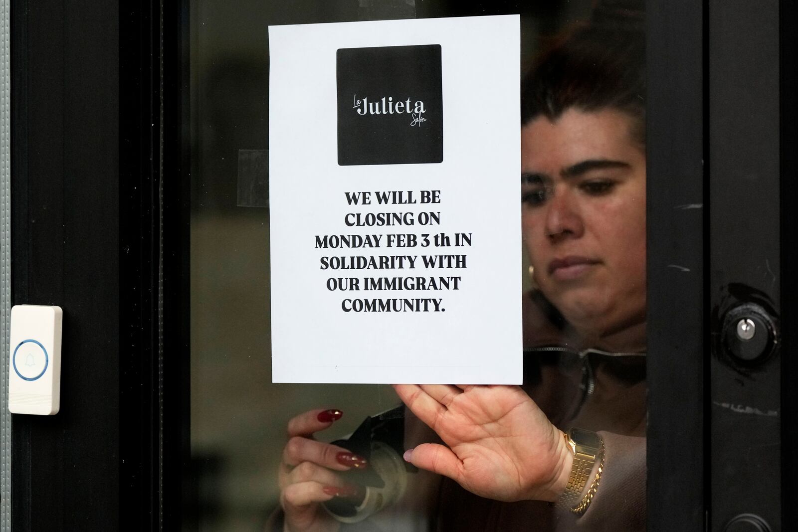 Andrea Toro, owner of La Julieta Salon, tapes a closure sign on her store in the Pilsen neighborhood of Chicago, to stand with immigrants, Monday, Feb. 3, 2025. (AP Photo/Nam Y. Huh)