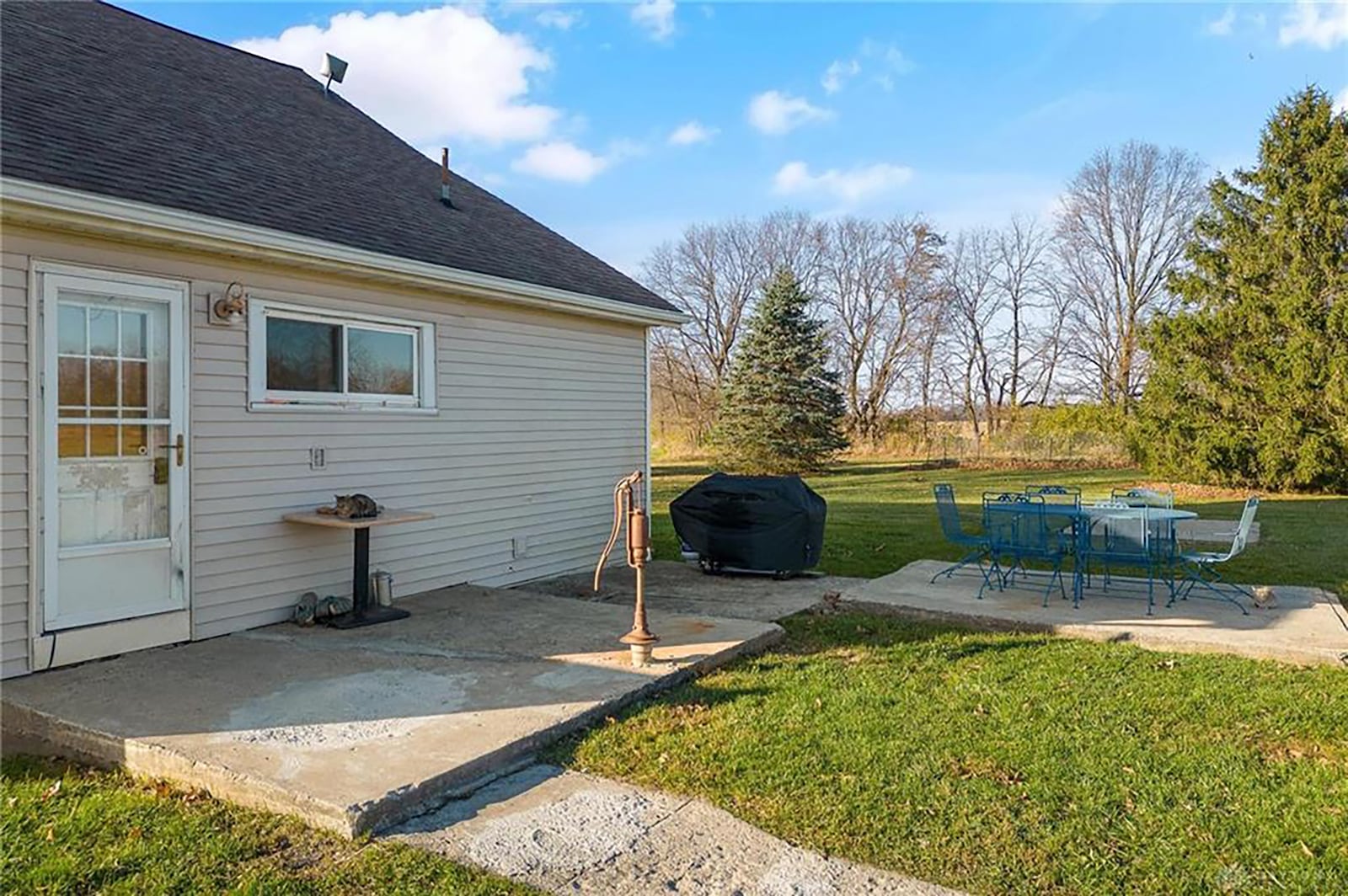 The rear of the home has two concrete patios and a storm door-covered back door leading into the kitchen.