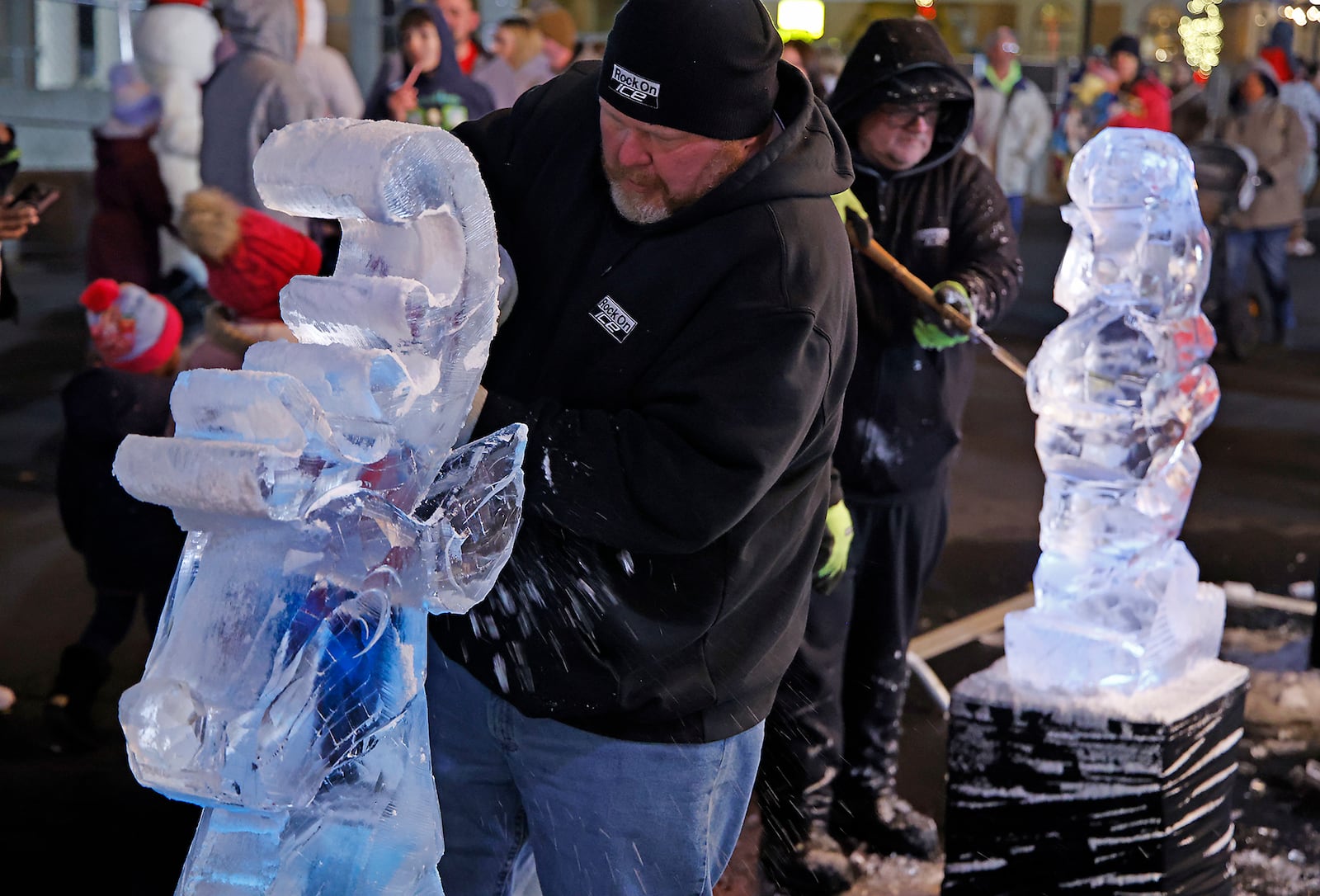 A crowd watches the crew from Rock On Ice carve holiday characters out of blocks of ice Friday, Nov. 24, 2023 during the Springfield Holiday in the City Grand Illumination. BILL LACKEY/STAFF