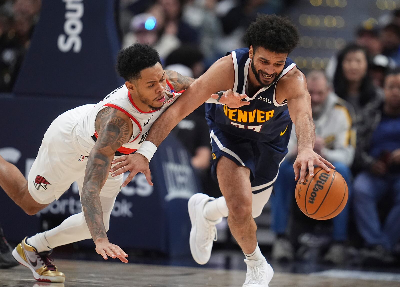 Denver Nuggets guard Jamal Murray, right, collects a loose ball as Portland Trail Blazers guard Anfernee Simons defends in the second half of an NBA basketball game Wednesday, Feb. 12, 2025, in Denver. (AP Photo/David Zalubowski)