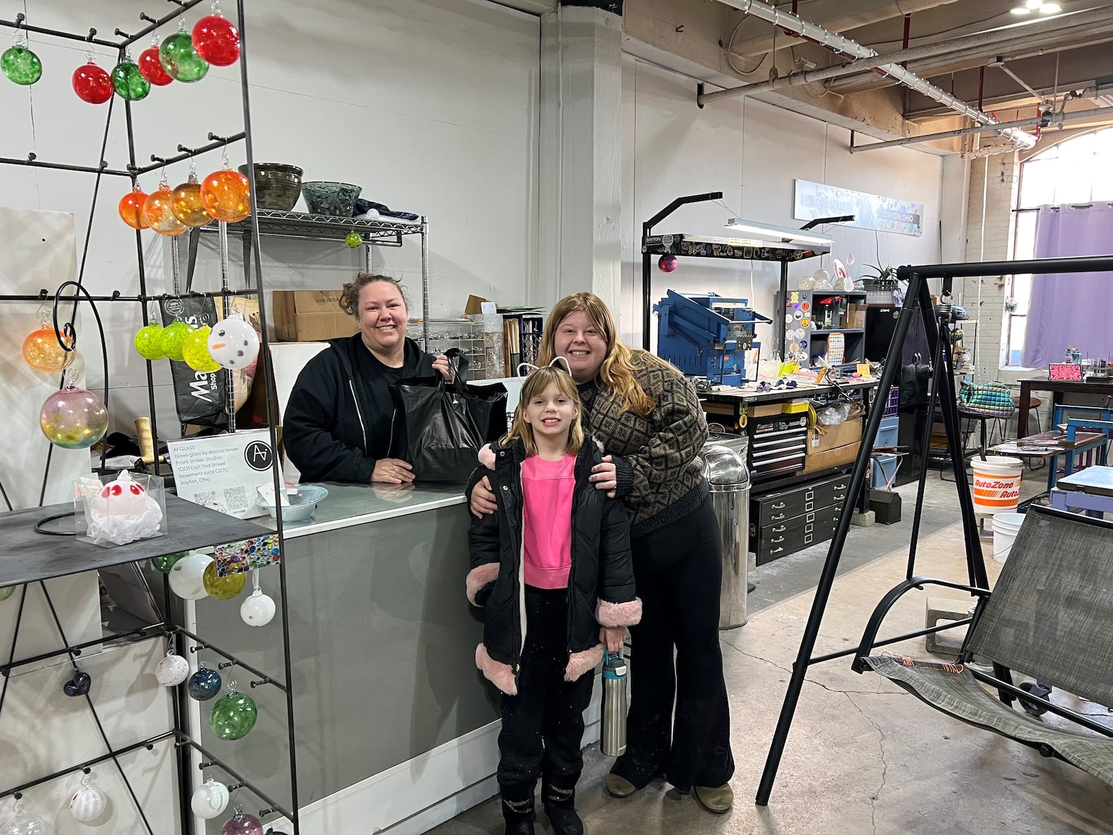 Ashley Knox, (right) bought blown glass ornaments at AV Glass in the Front Street arts district on Sunday, Dec. 22, 2024. From left are owner and artist Abiona Teague and Athena Ropp, 8. LYNN HULSEY/STAFF