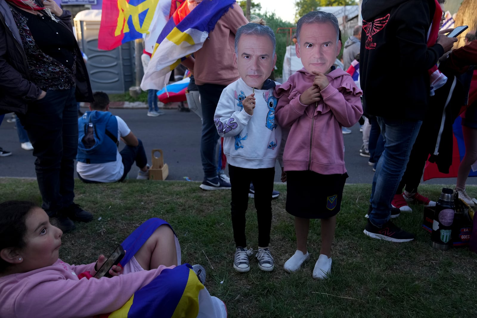 Children hold up masks of Frente Amplio presidential candidate Yamandu Orsi as they wait for the start of his closing rally ahead of the presidential run-off election in Las Piedras, Uruguay, Wednesday, Nov. 20, 2024. (AP Photo/Matilde Campodonico)