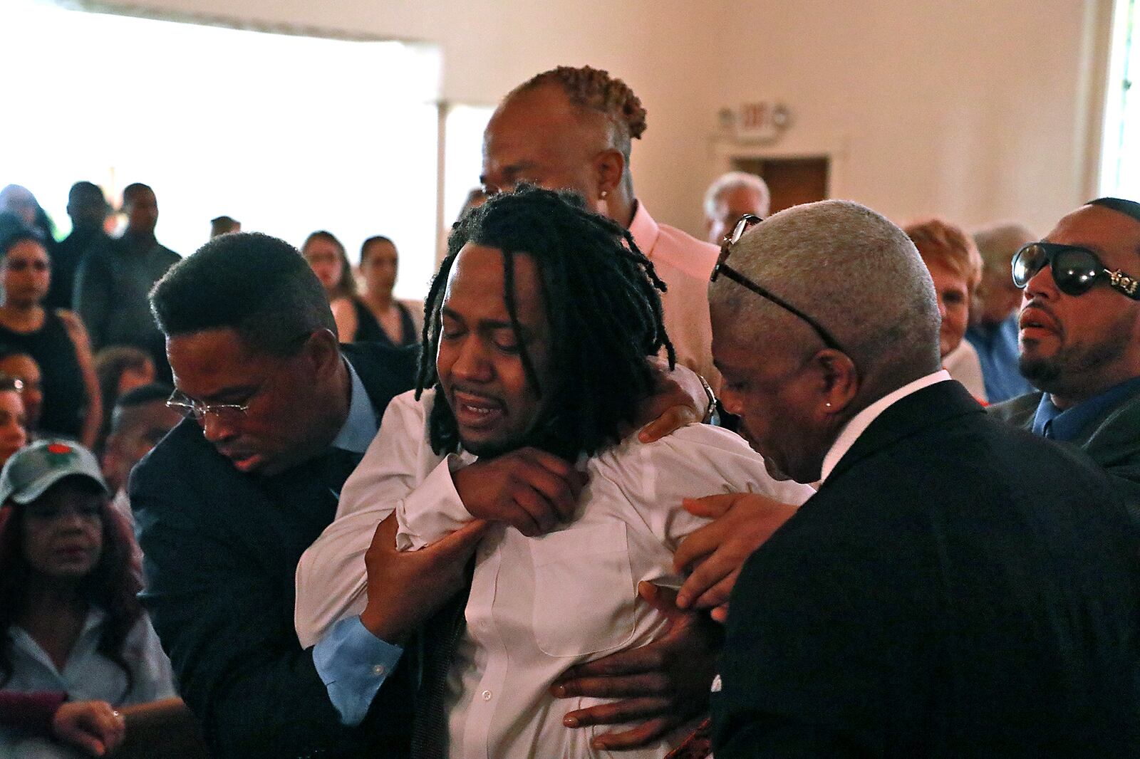 Dion Green is helped up after he collapsed during the funeral service for his father, Derrick Fudge, Saturday at St. John Missionary Baptist Church in Springfield. Fudge was one of the nine people killed last Sunday in a mass shooting in the Oregon District in Dayton. BILL LACKEY/STAFF