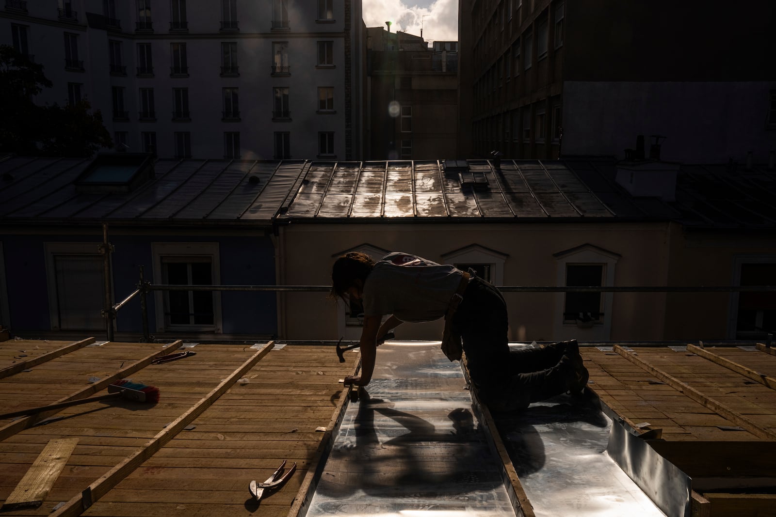 A roofer installs zinc sheets on a building in Paris, Friday, Oct. 22, 2024. (AP Photo/Louise Delmotte)