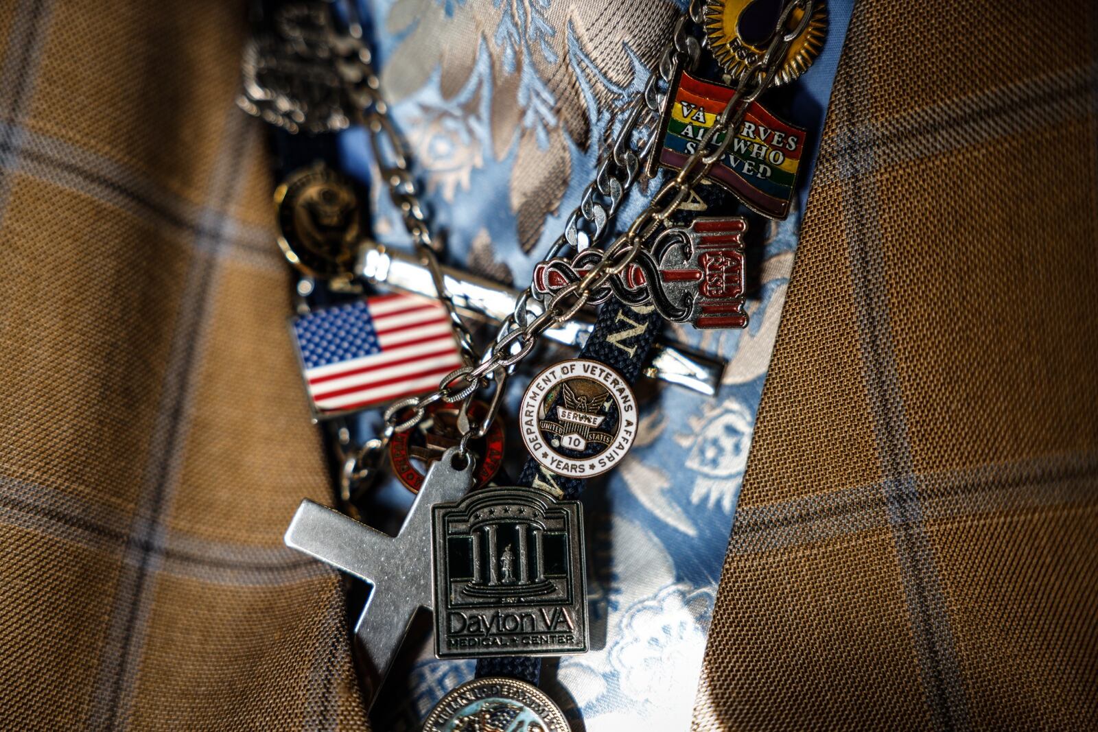 Clarence T. Jennings, is a vocational rehab specialist at the Dayton Veterans Affairs Medical Center. A veteran who struggled with addiction and attempted suicide, he is now 12 years sober and has turned his life around after getting help at the VA. He accents his workwear with these medallions, a cross and other meaningful items. JIM NOELKER/STAFF