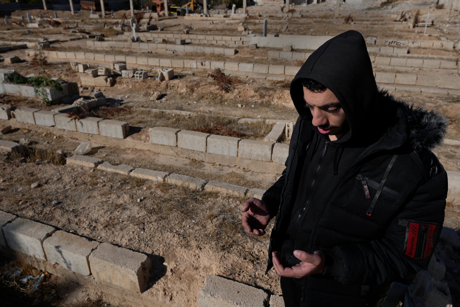 A Syrian man prays at a mass grave where they buried those who were killed by the sarin struck during a 2013 chemical weapons attack that was blamed on then President Bashar Assad's forces, in Zamalka neighbourhood, on the outskirts of Damascus, Syria, Wednesday, Dec. 25, 2024. (AP Photo/Hussein Malla)