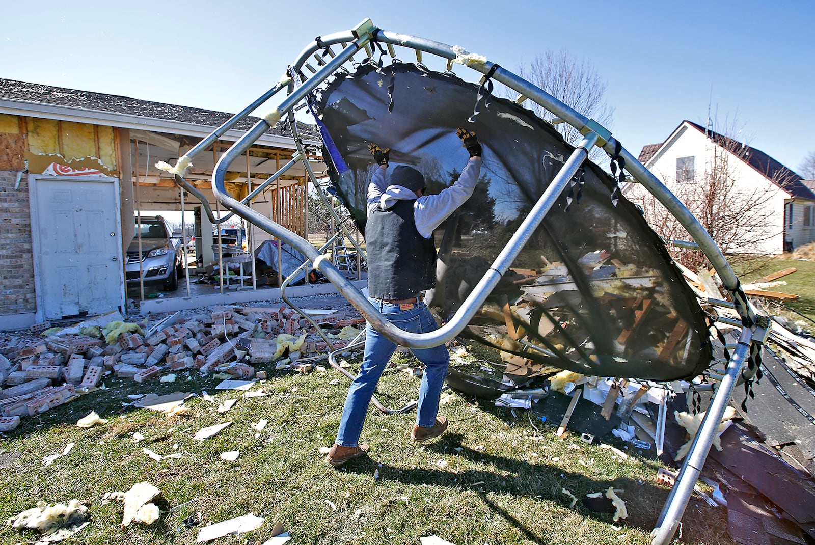 Jake Martin flips a broken trampoline onto a garbage pile as he helps his brother, Andy, clean up his yard Thursday, Feb. 29, 2024. Andy's house was one of several damaged by the tornado Wednesday morning along Mitchell Road. BILL LACKEY/STAFF