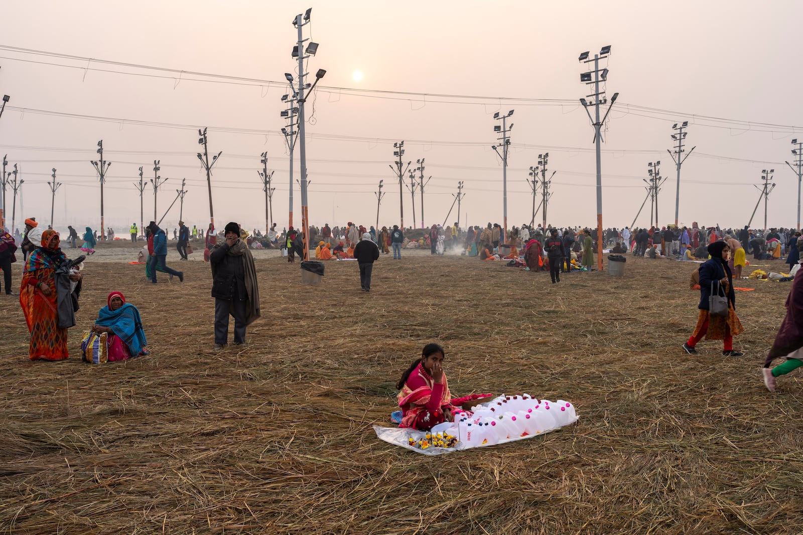 A woman sells empty plastic containers as devotees arrive to bathe at the confluence of the Ganges, the Yamuna and the mythical Saraswati rivers, a day before the official beginning of the 45-day-long Maha Kumbh festival, in Prayagraj, India, Sunday, Jan. 12, 2025. (AP Photo/Ashwini Bhatia)