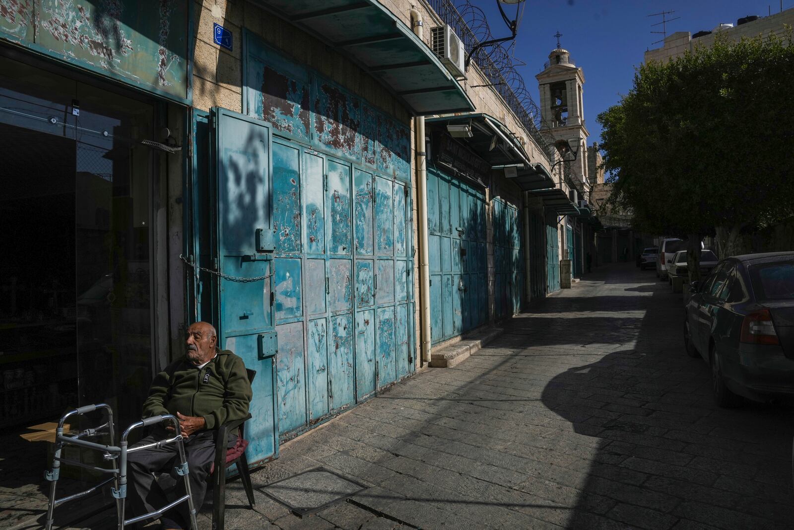 A man rests by a row of empty shops near the Church of the Nativity, where Christians believe Jesus Christ was born, ahead of Christmas in the West Bank city of Bethlehem, Tuesday, Dec. 17, 2024. (AP Photo/Mahmoud Illean)