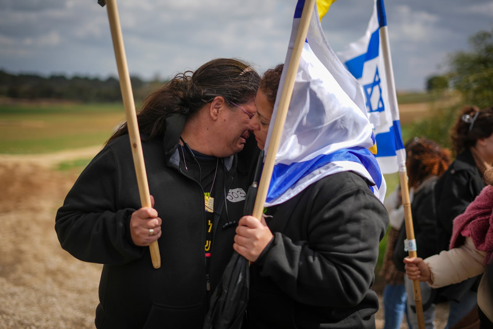 A woman reacts as a convoy carrying the coffins containing the bodies of four Israeli hostages, including a mother and her two children, just handed over by Palestinian militant groups in Gaza, drives by a road near Kibbutz Reim, southern Israel, Thursday, Feb. 20, 2025.(AP Photo/Ariel Schalit)