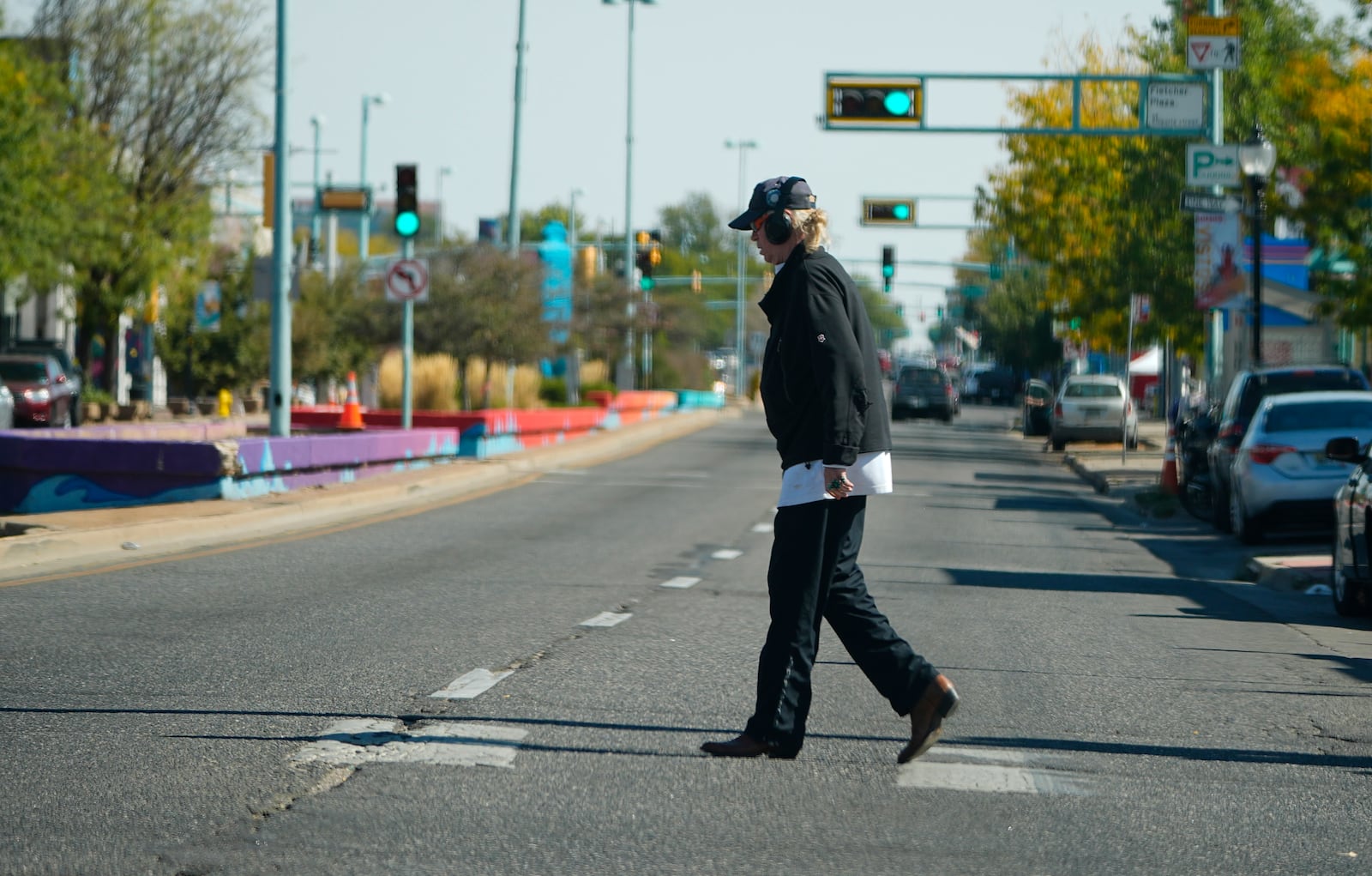 A lone pedestrian crosses East Colfax Avenue at the intersection with Dayton Street, Wednesday, Oct. 9, 2024, in the east Denver suburb of Aurora, Colo. (AP Photo/David Zalubowski)