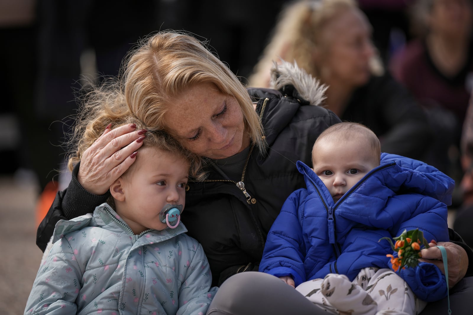 A woman holds two children at "Hostages Square" in Tel Aviv, Israel, Thursday, Feb. 20, 2025, after Palestinian militant groups handed over the bodies of four Israeli hostages, including a mother and her two children, to the Red Cross in Gaza. (AP Photo/Oded Balilty)