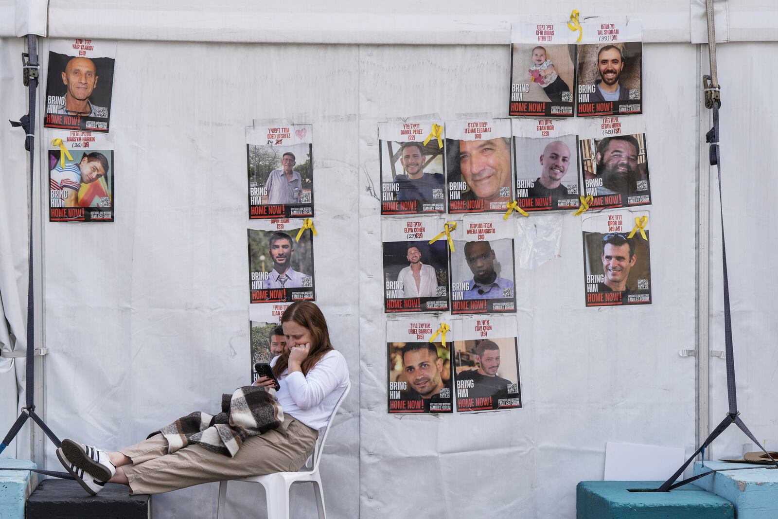 A woman sits at the so-called 'Hostages Square' in Tel Aviv, Israel, Thursday, Feb. 20, 2025, as the bodies of four Israeli hostages, including a mother and her two children, are handed over by Hamas to the Red Cross in Gaza. (AP Photo/Oded Balilty)