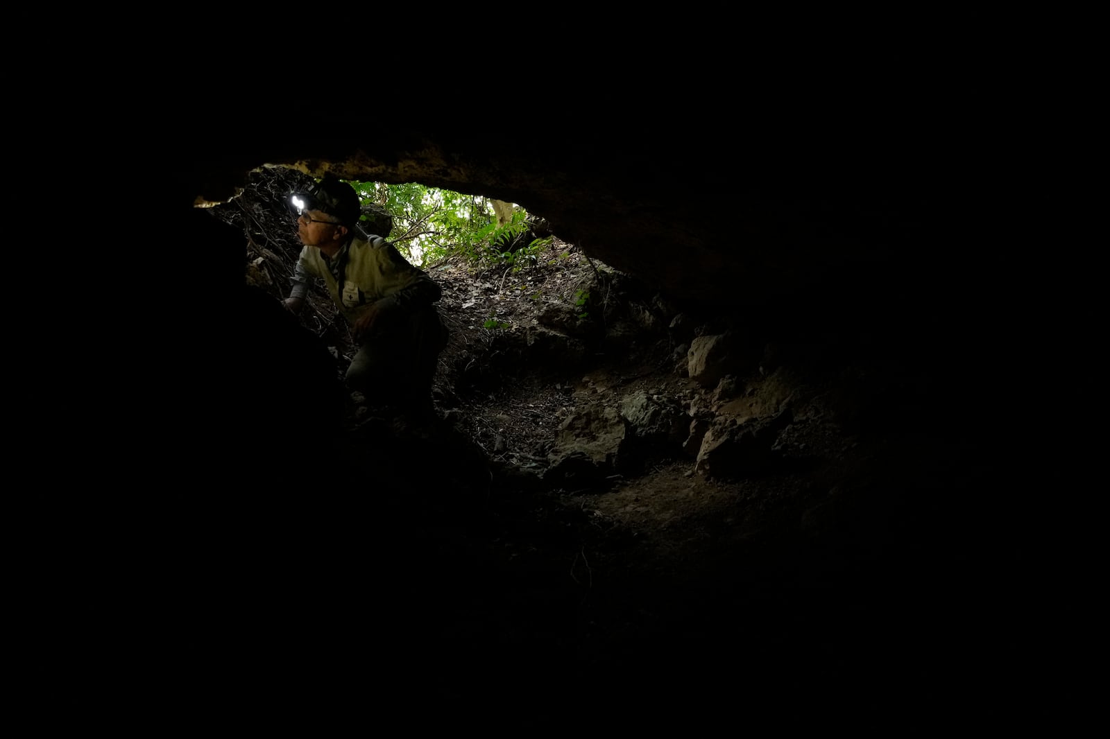 Takamatsu Gushiken, a "gamafuya," an Okinawa dialect meaning a person who digs in a cave, looks at the wall of a cave while searching for the remains of those who died during the Battle of Okinawa towards the end of the World War II in 1945, in Itoman, on the main island of the Okinawa archipelago, southern Japan, Saturday, Feb. 15, 2025. (AP Photo/Hiro Komae)