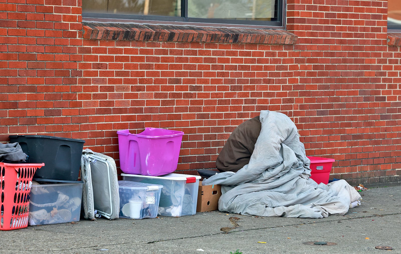 A homeless person tries hide from the morning chill under a blanket Thursday, Nov. 7, 2024 along West Main Street in Springfield. BILL LACKEY/STAFF