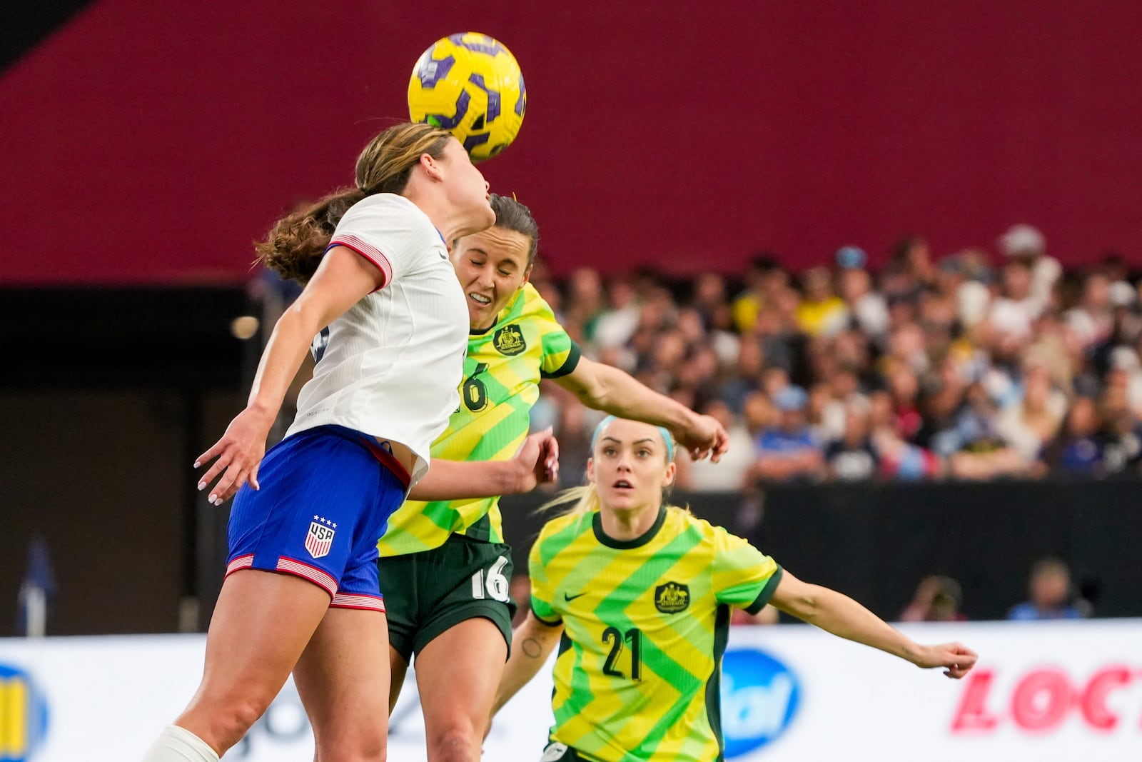 United States forward Emma Sears and Australia forward Hayley Raso jump to head the ball while Australia defender Ellie Carpenter (21) watches during the first half of a group stage match in the SheBelieves Cup women's soccer tournament, Sunday, Feb. 23, 2025, in Glendale, Ariz. (AP Photo/Samantha Chow)