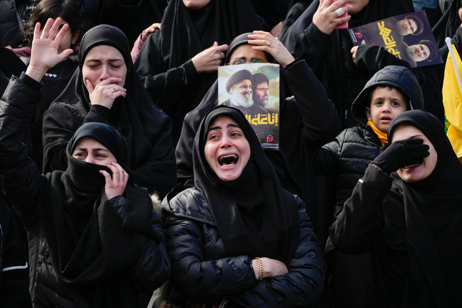 Mourners react as a trailer carrying the coffins containing the bodies of Hezbollah's former leader Hassan Nasrallah and his cousin and successor Hashem Safieddine drives through the crowd at the beginning of a funeral procession in the Sports City Stadium in Beirut, Lebanon, Sunday, Feb. 23, 2025. (AP Photo/Hussein Malla)