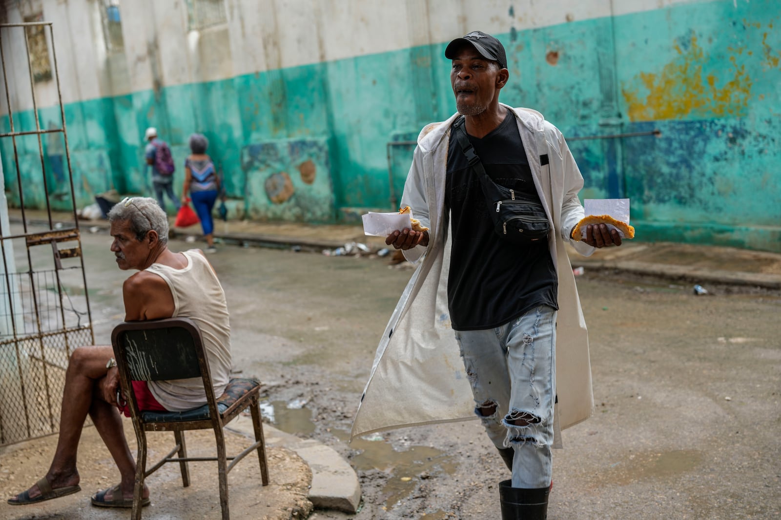 A man walks down the street holding slices of pizza during a massive blackout following the failure of a major power plant in Havana, Cuba, Saturday, Oct. 19, 2024. (AP Photo/Ramon Espinosa)