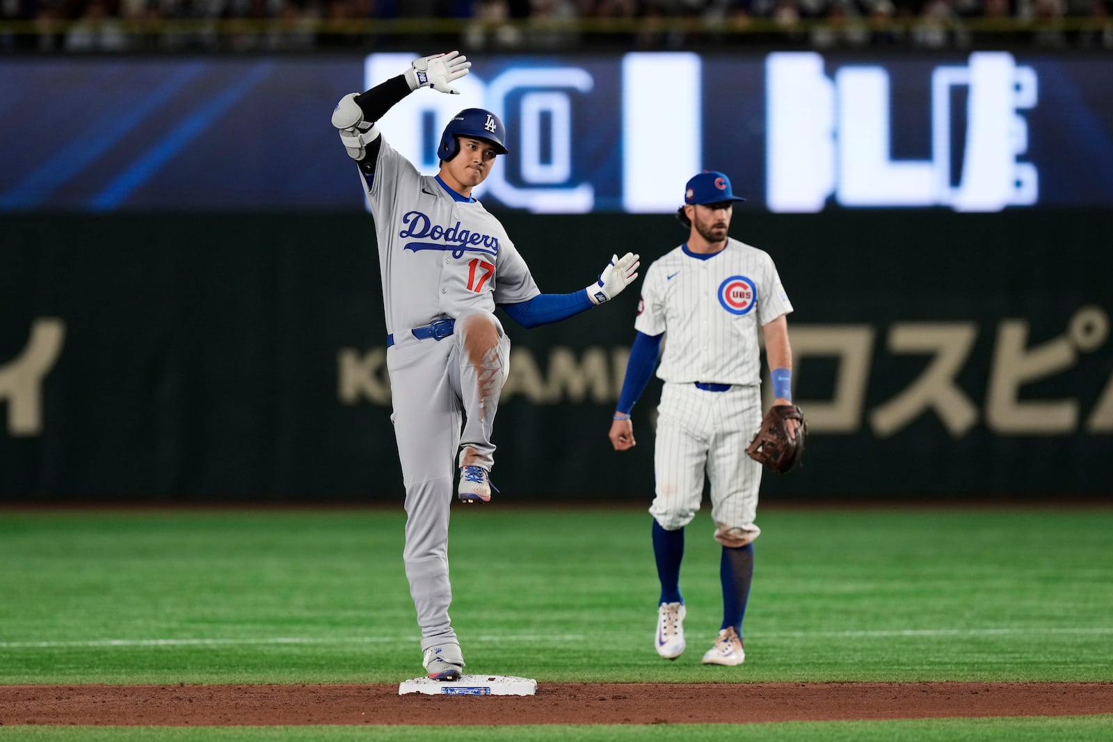 Los Angeles Dodgers' Shohei Ohtani, left, celebrates his double as Chicago Cubs' Dansby Swanson, right, stands by the bag in the ninth inning of an MLB Japan Series baseball game in Tokyo, Japan, Tuesday, March 18, 2025. (AP Photo/Eugene Hoshiko)