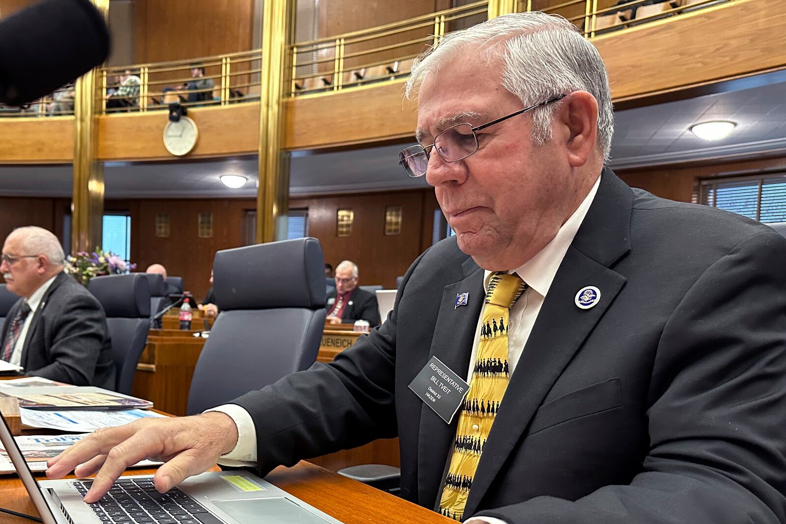 North Dakota Republican state Rep. Bill Tveit works at his desk on Wednesday, Jan. 22, 2025, in the House of Representatives at the state Capitol in Bismarck, N.D. (AP Photo/Jack Dura)