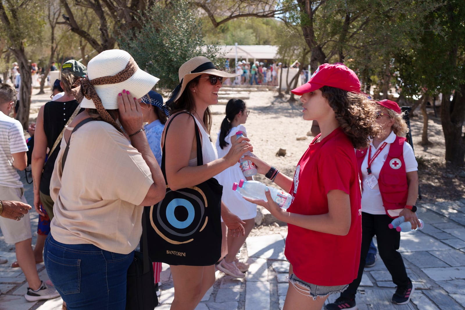 FILE - A Red Cross volunteer gives water to tourists at the foot of the Acropolis hill during a hot and windy day in Athens, July 17, 2024. (AP Photo/Petros Giannakouris, File)