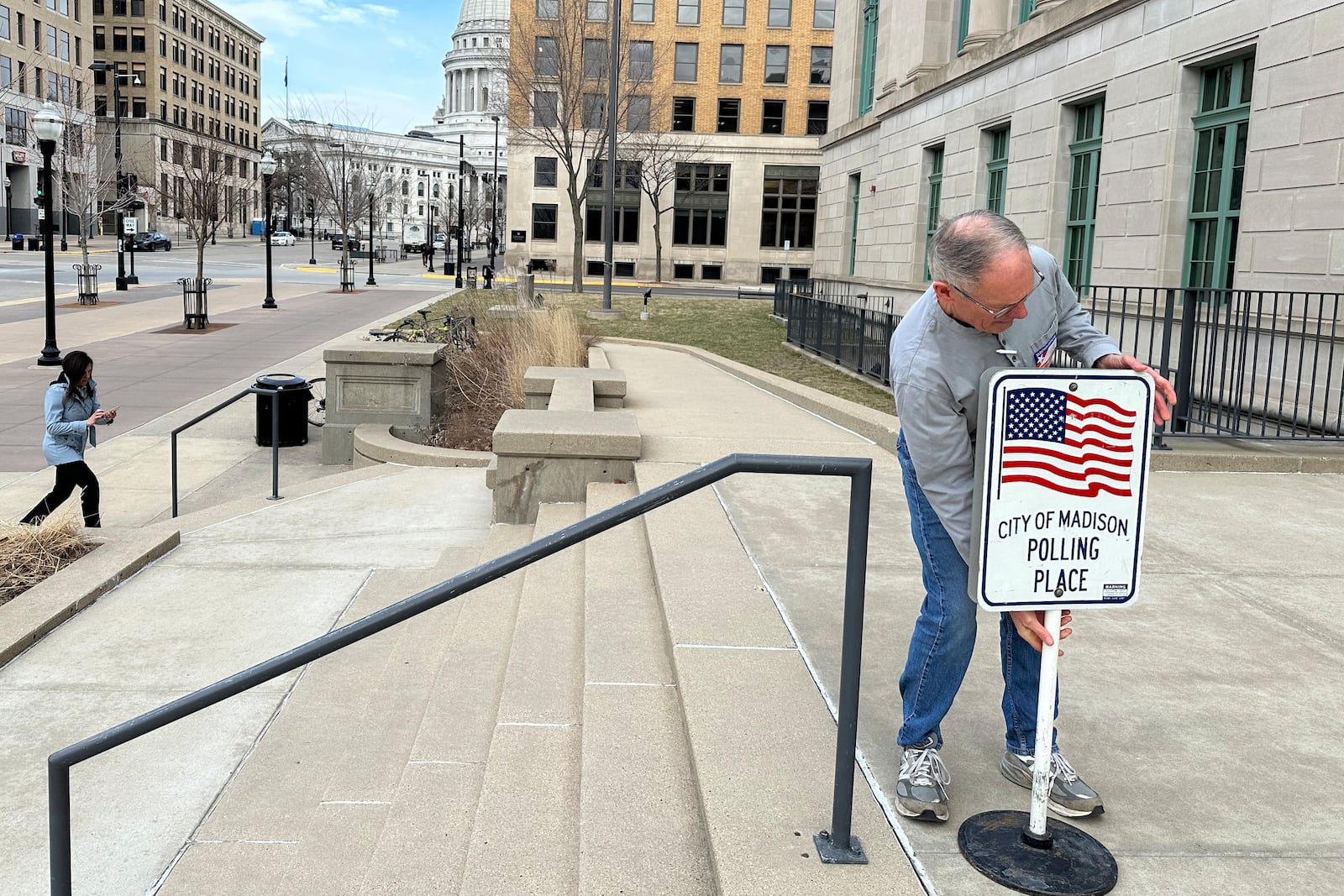 Volunteer Wade DallaGrana puts out a sign ahead of the start of early voting in the Wisconsin Supreme Court race on Tuesday, March 18, 2025, in Madison, Wisconsin. (AP Photo/Scott Bauer)