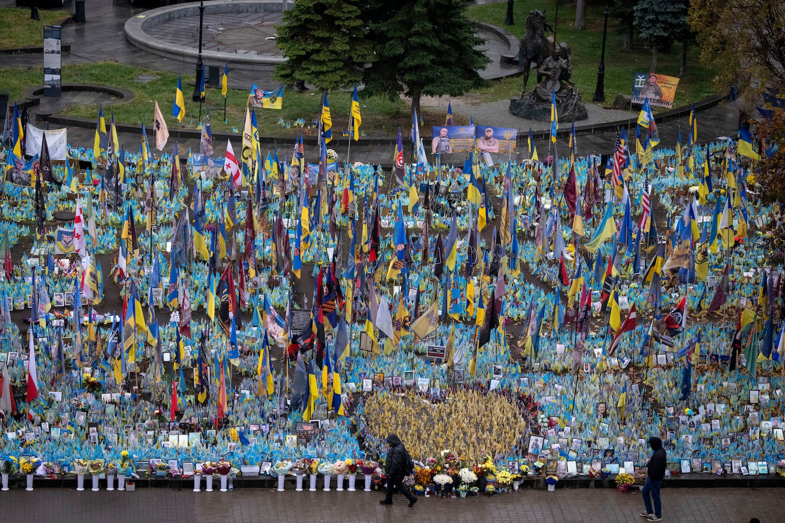 People walk past the memorial to fallen soldiers in Independence Square in Kyiv, Ukraine, Friday, Nov. 15, 2024. (AP Photo/Efrem Lukatsky)