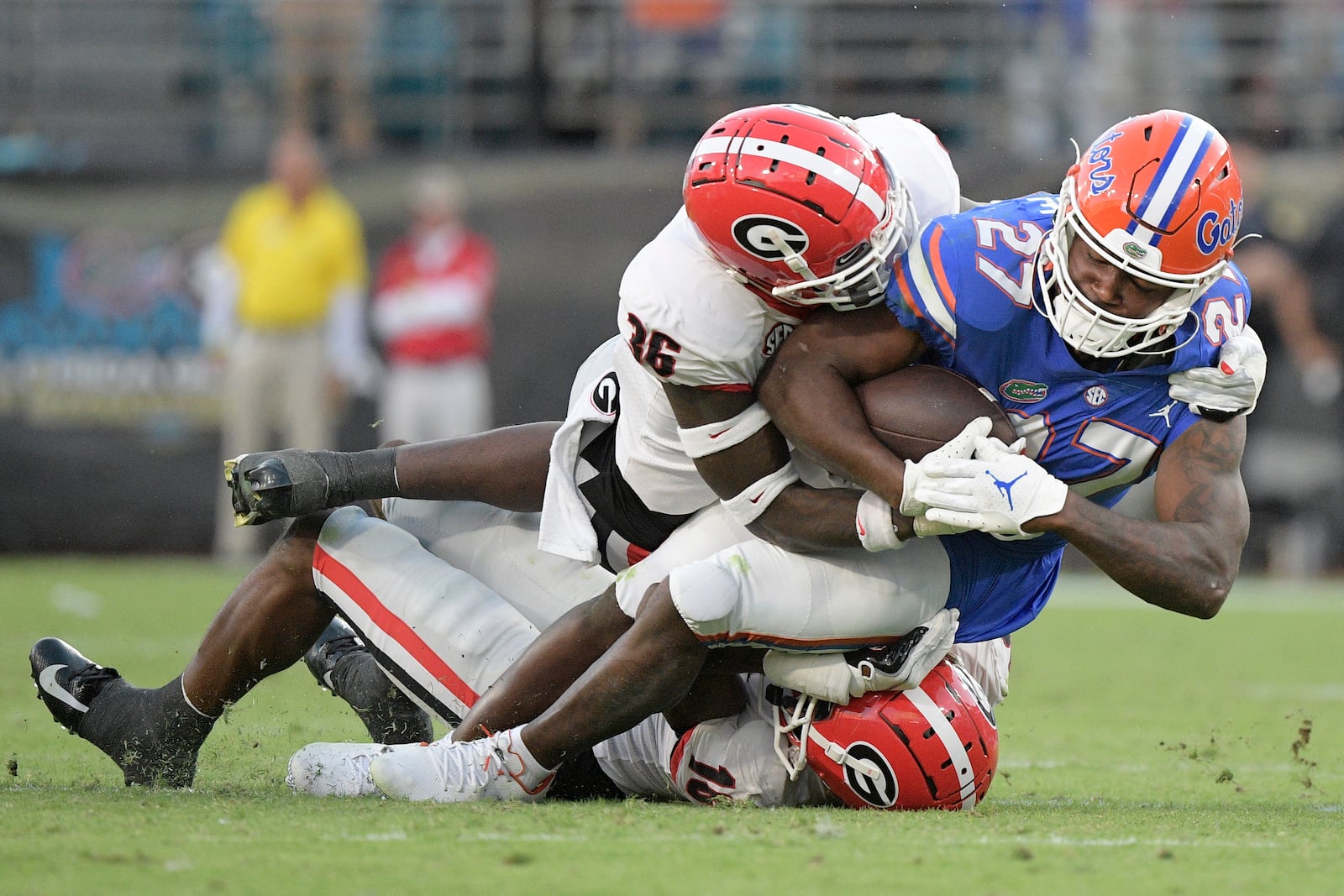 Florida running back Dameon Pierce (27) is tackled by Georgia defensive back Latavious Brini (36) and defensive back Lewis Cine (16), below, after rushing during the second half of an NCAA college football game, Saturday, Oct. 30, 2021, in Jacksonville, Fla. (AP Photo/Phelan M. Ebenhack)