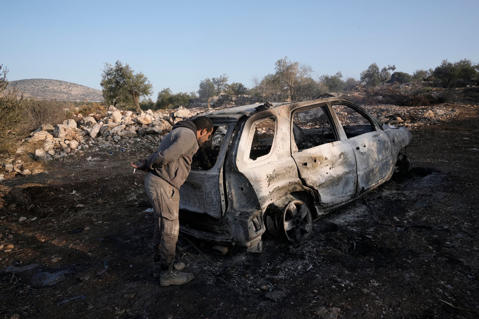 A Palestinian inspects the car that was targeted in an Israeli airstrike that the military said was targeting a militant cell near the West Bank village of Al-Aqaba, Tuesday Dec. 3, 2024. (AP Photo/Majdi Muhammad)