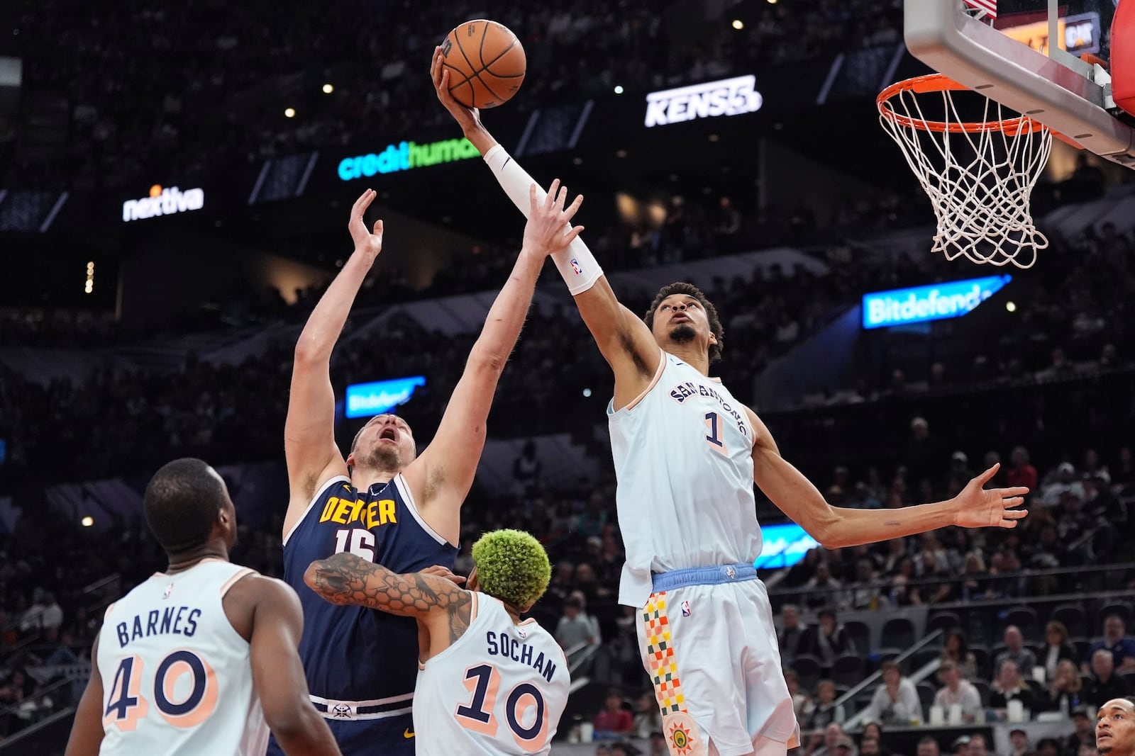 San Antonio Spurs center Victor Wembanyama (1) grabs a rebound over Denver Nuggets center Nikola Jokic (15) during the first half of an NBA basketball game in San Antonio, Saturday, Jan. 4, 2025. (AP Photo/Eric Gay)