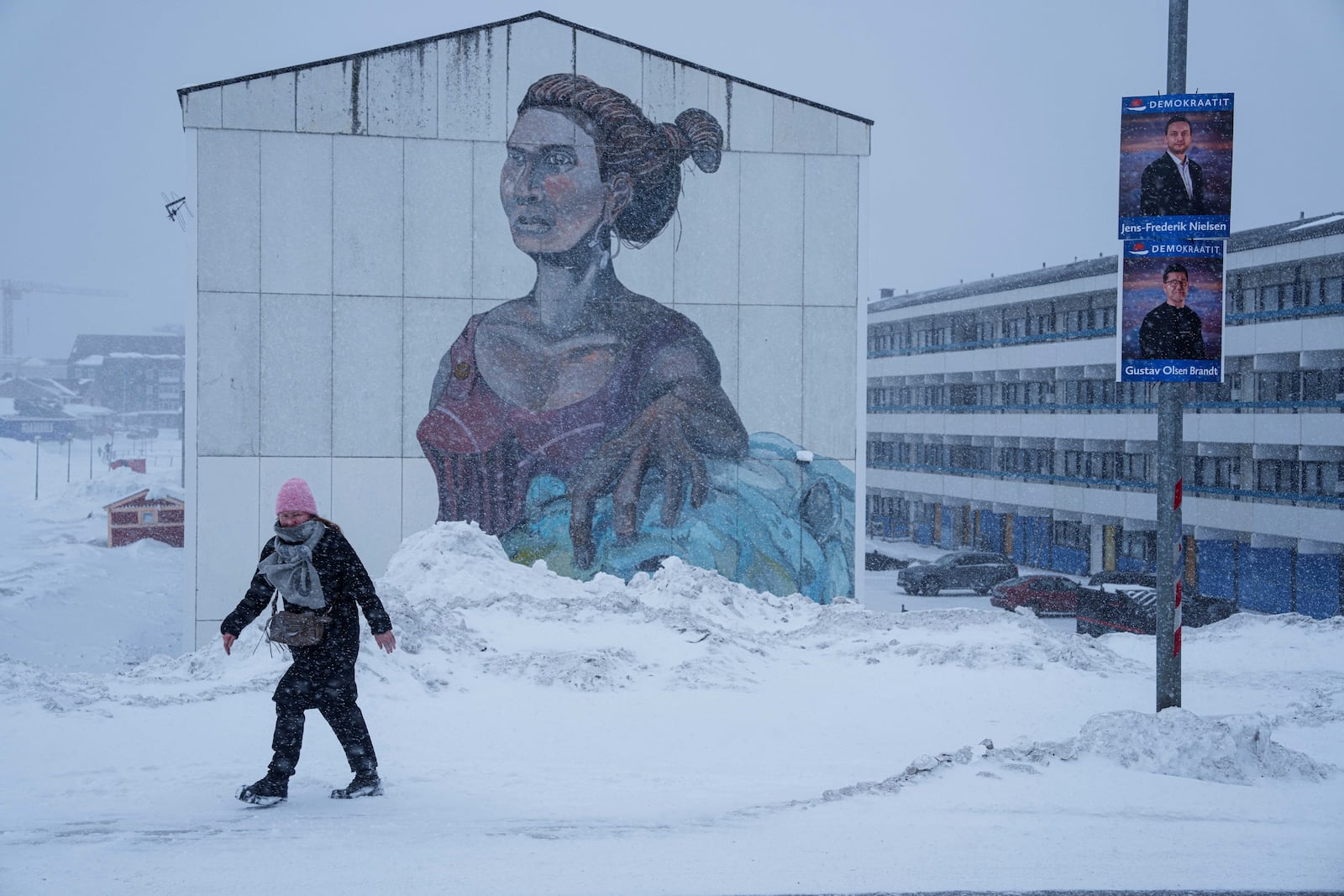 FILE - A woman walks on a street with political placards for the upcoming elections in Nuuk, Greenland, Saturday, March 8, 2025. (AP Photo/Evgeniy Maloletka, File)