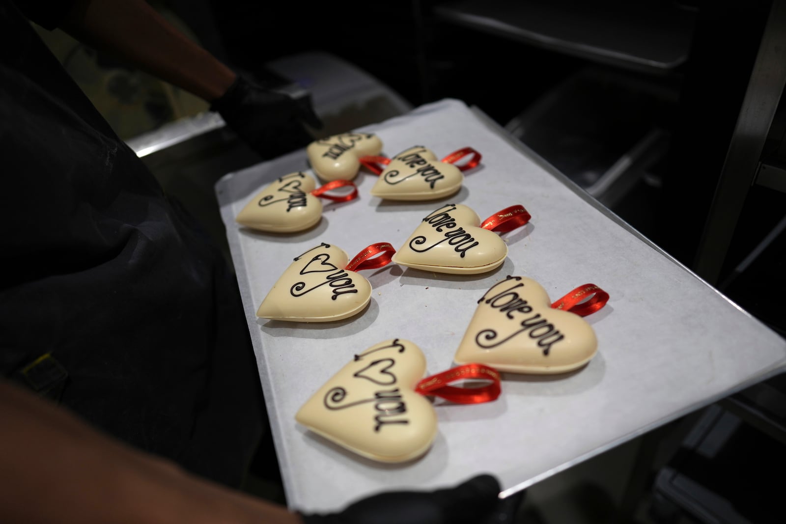 A worker holds chocolate Valentine hearts on a drying tray in the workshop at The Chocolate Line in Bruges, Belgium, Thursday, Feb. 6, 2025. (AP Photo/Virginia Mayo)