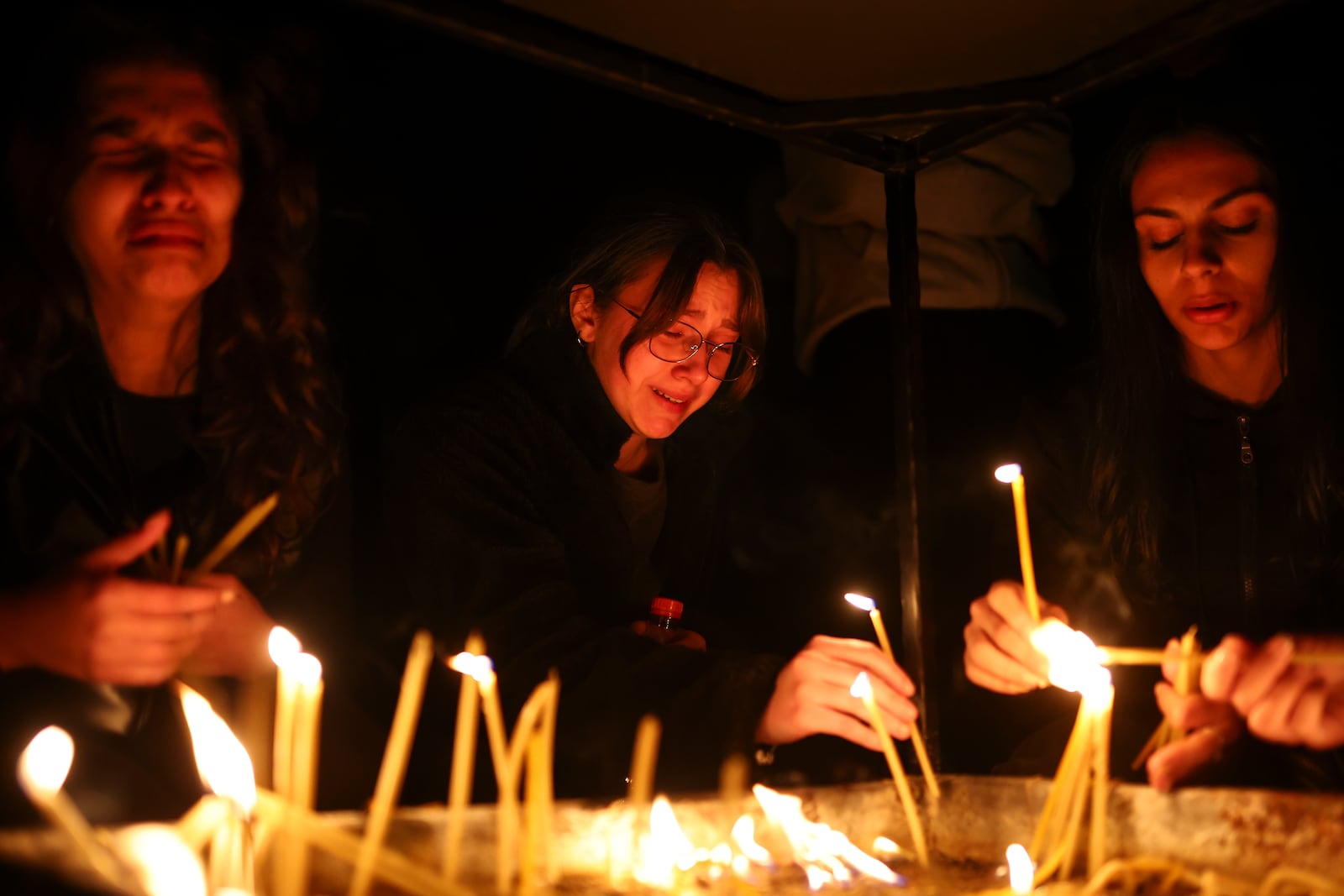 Girls cry as they light candles in the town of Kocani, North Macedonia, Sunday, March 16, 2025, following a massive fire in the nightclub early Sunday. (AP Photo/Armin Durgut)