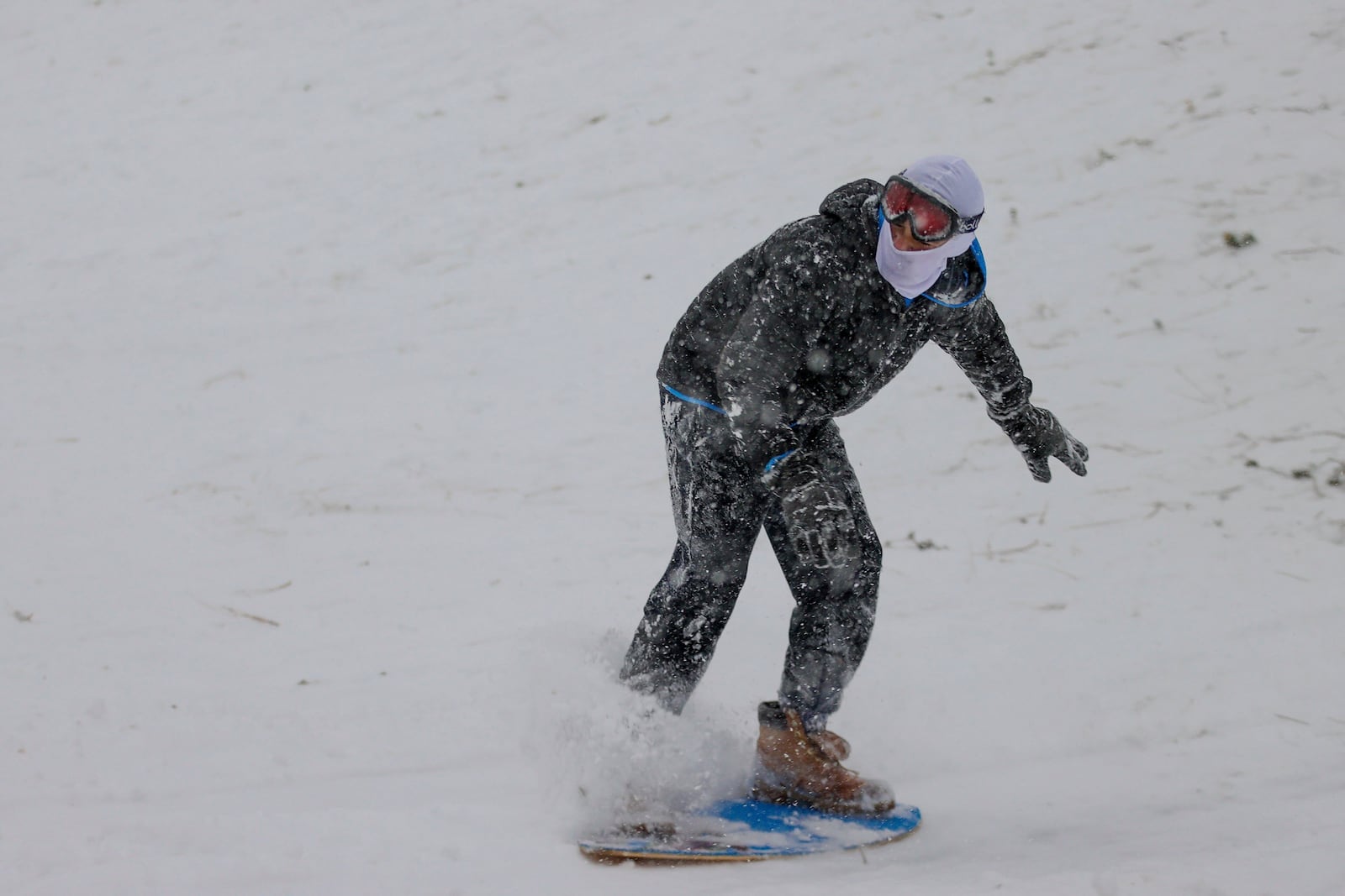 Matthey Shashaty, 12, uses a skim board snow at Bayview Park on Tuesday, Jan. 21, 2025, in Pensacola, Fla. (Luis Santana/Tampa Bay Times via AP)