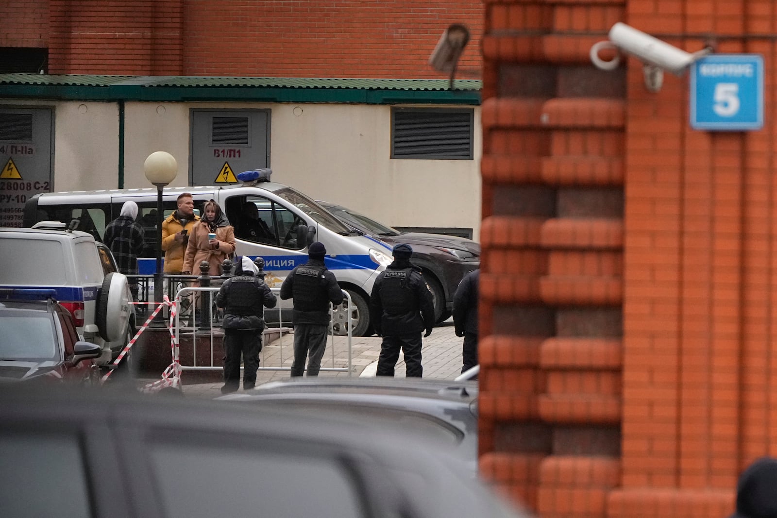 Investigators and police officers stand in the yard of an upscale residential block in Moscow, Russia, Monday, Feb. 3, 2025, where the blast has killed one person and wounded four others, Russian news agencies say. (AP Photo/Alexander Zemlianichenko)