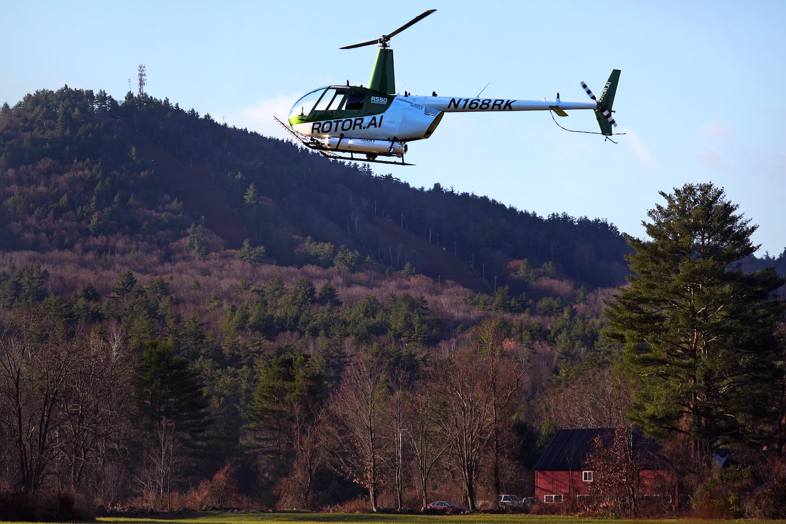 A Rotor Technologies unmanned semi-autonomous helicopter flies near Pat's Peak ski area, rear, during a test flight over Intervale Airport, Monday, Nov. 11, 2024, in Henniker, N.H. (AP Photo/Charles Krupa)