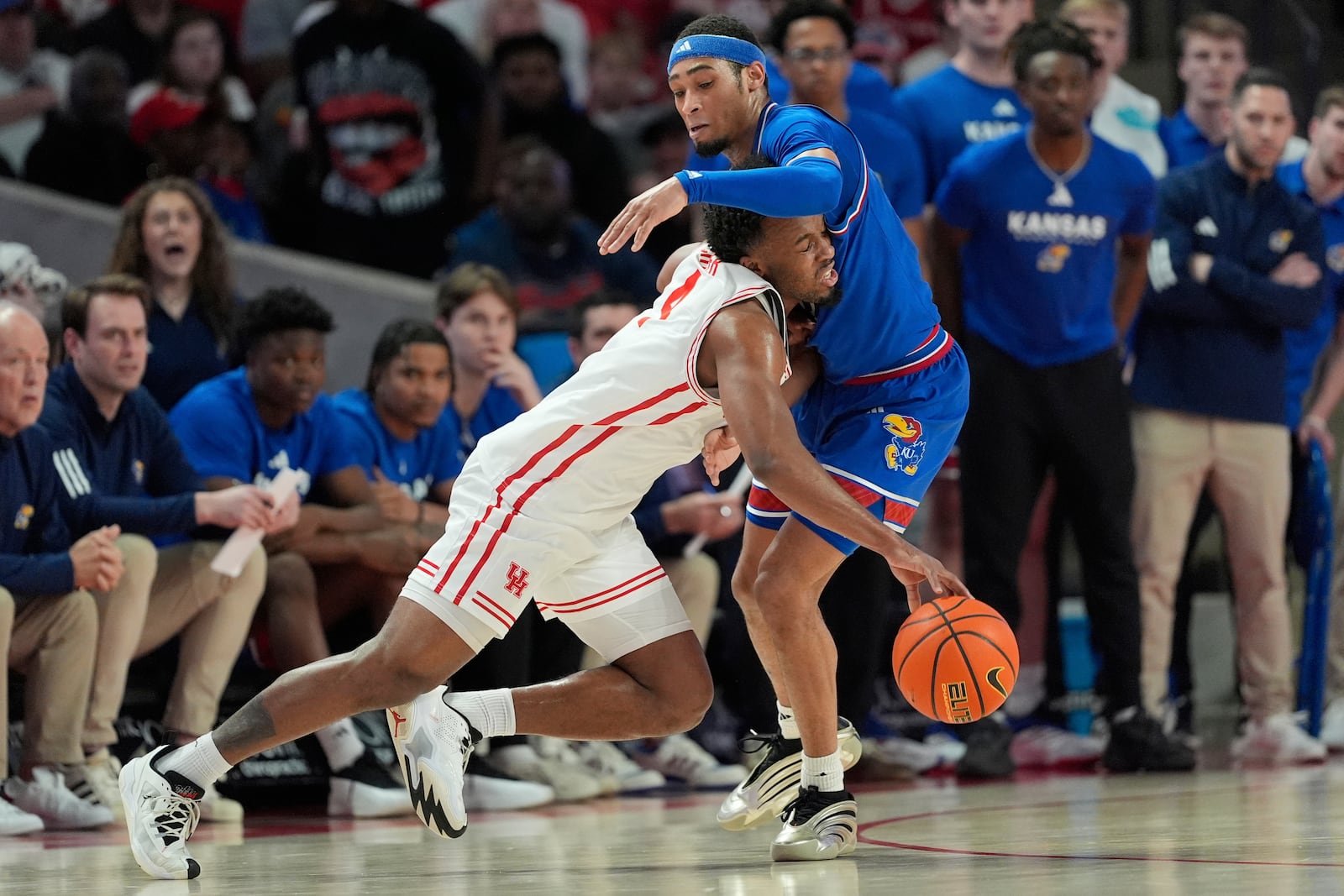 Houston's L.J. Cryer, left, collides with Kansas' Dajuan Harris Jr. during the first half of an NCAA college basketball game Monday, March 3, 2025, in Houston. (AP Photo/David J. Phillip)