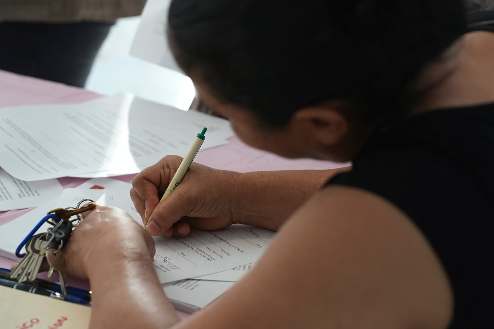 A young mother signs a form giving Nora Sandigo legal guardianship of her children if she is detained or deported by immigration authorities, Sunday, Jan. 19, 2025, in Miami. (AP Photo/Marta Lavandier)