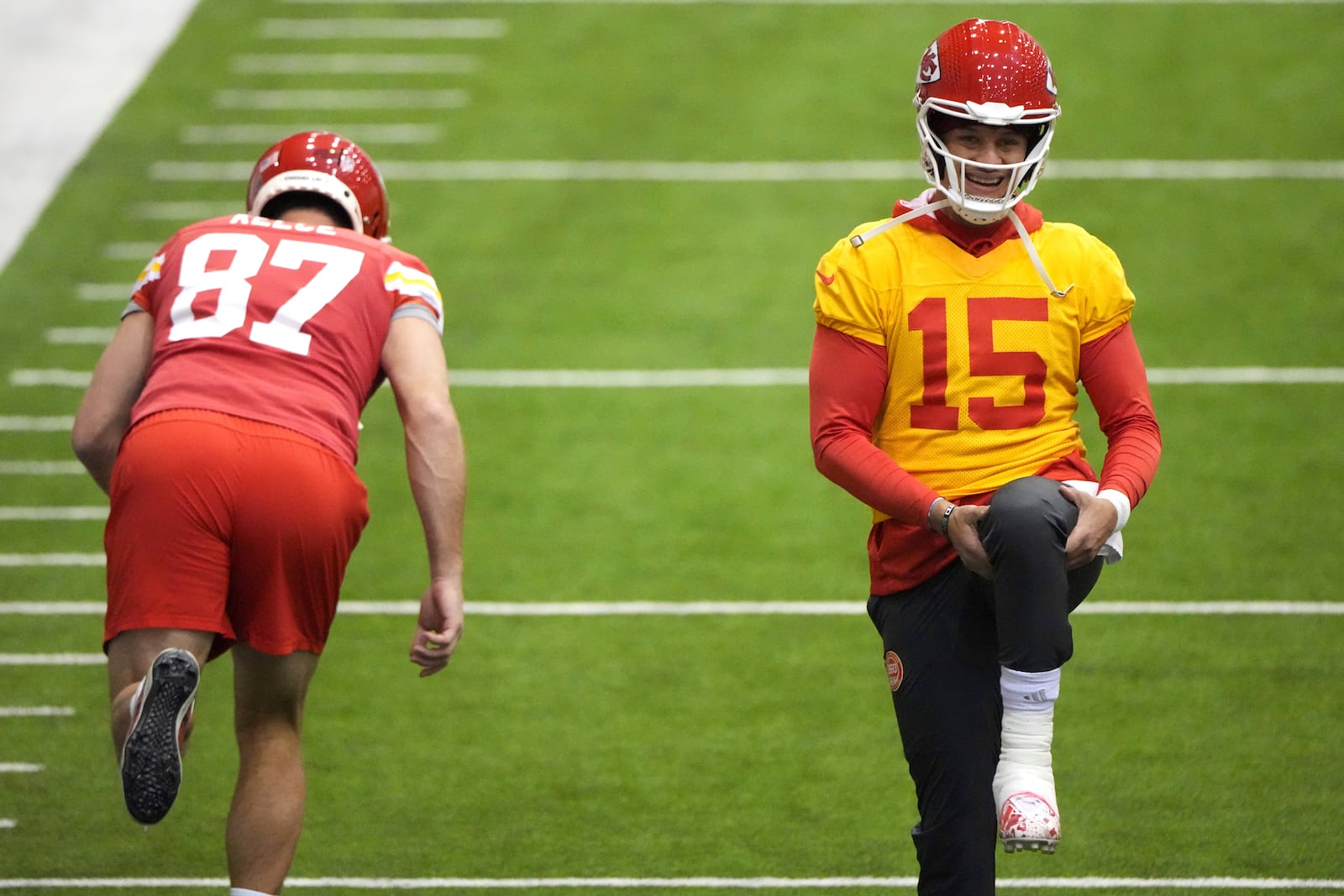 Kansas City Chiefs quarterback Patrick Mahomes (15) and tight end Travis Kelce (87) stretch during the team's NFL football practice Thursday, Jan. 23, 2025, in Kansas City, Mo. (AP Photo/Charlie Riedel)