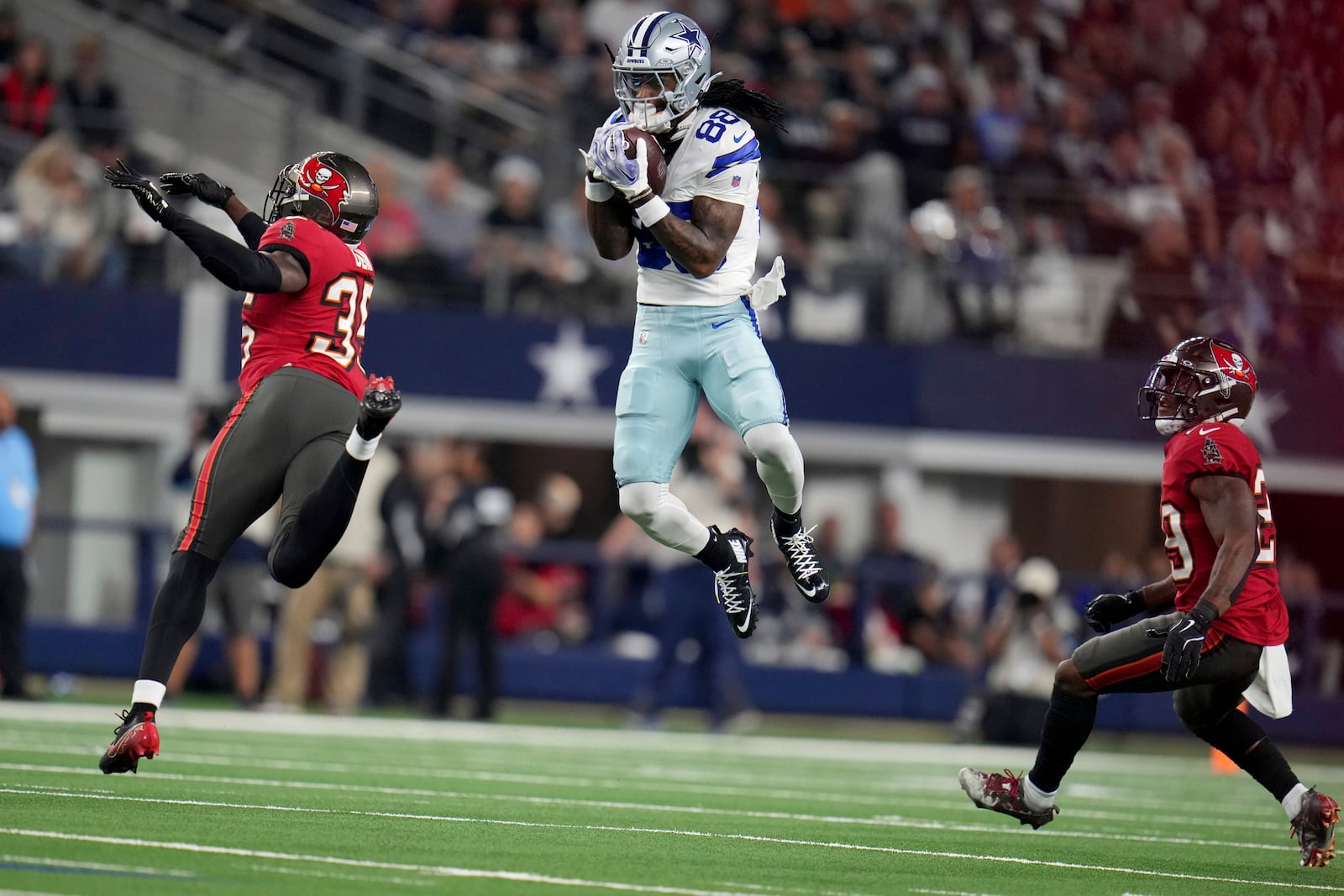 Dallas Cowboys wide receiver CeeDee Lamb (88) catches a pass between Tampa Bay Buccaneers cornerback Jamel Dean (35) and Christian Izien (29) in the first half of an NFL football game in Arlington, Texas, Sunday, Dec. 22, 2024. (AP Photo/Julio Cortez)