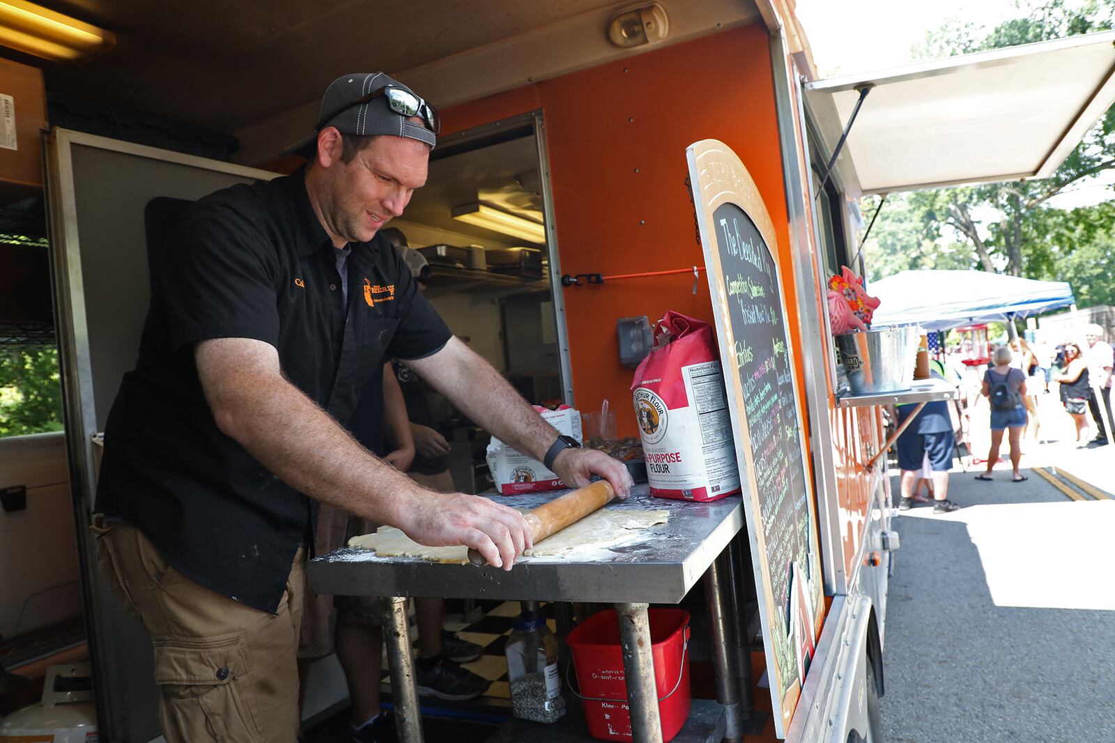 Caleb Stringer, from  the Bearded Pig food truck, rolls out dough for their brisket meat pies Saturday at the Food Truck Competition in Veterans Park. BILL LACKEY/STAFF