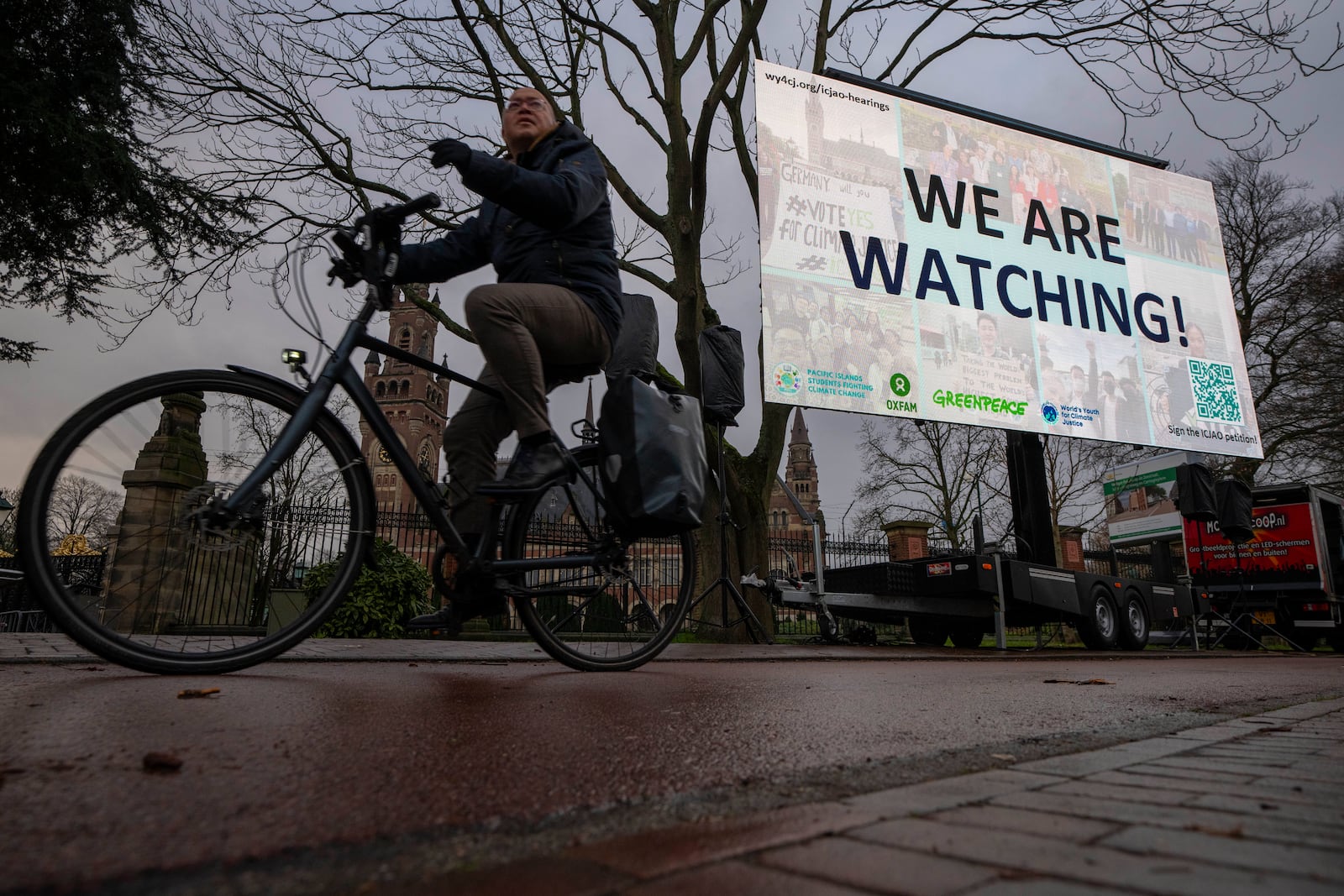 Activists put up a billboard outside the International Court of Justice, in The Hague, Netherlands, as it opens hearings into what countries worldwide are legally required to do to combat climate change and help vulnerable nations fight its devastating impact, Monday, Dec. 2, 2024. (AP Photo/Peter Dejong)