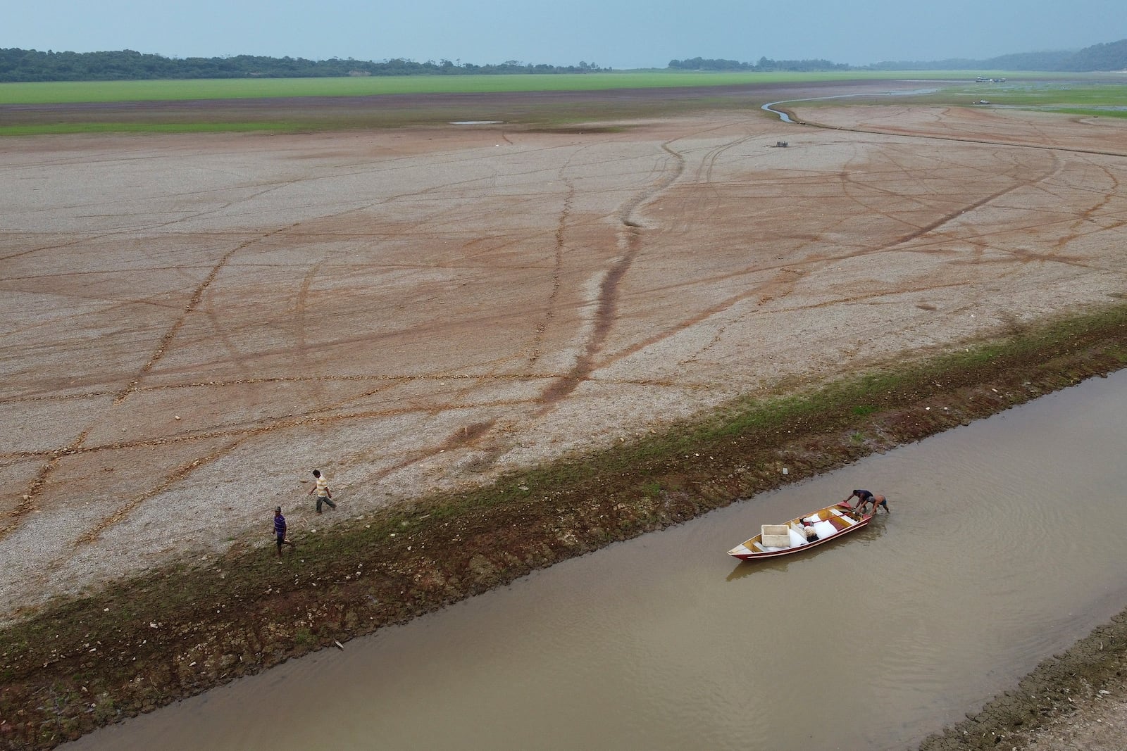 FILE - Fishermen push a boat in the Aleixo Lake amid a drought in Manaus, Amazonas state, Brazil, Sept. 24, 2024. (AP Photo/Edmar Barros, File)