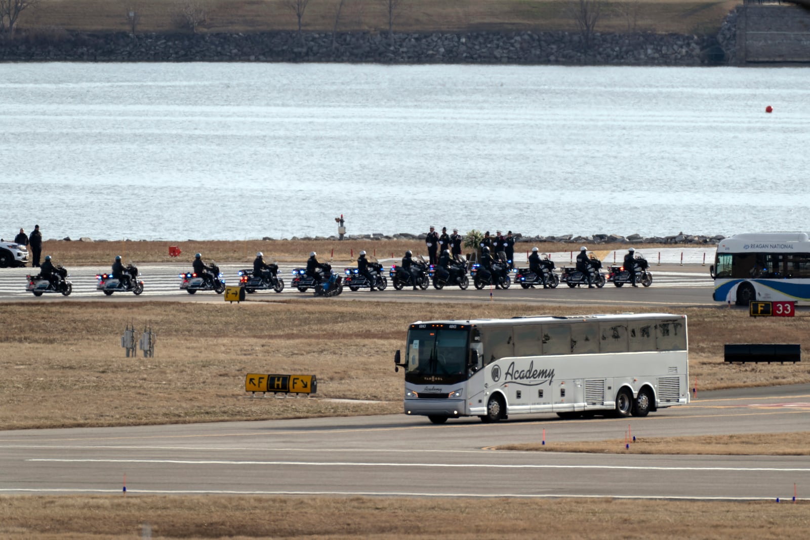 Buses carrying family members of the victims of a mid-air collision between an American Airlines jet and an Army helicopter arrive to runway 33 near the wreckage site in the Potomac River at Ronald Reagan Washington National Airport, Sunday, Feb. 2, 2025, in Arlington, Va. (AP Photo/Jose Luis Magana)