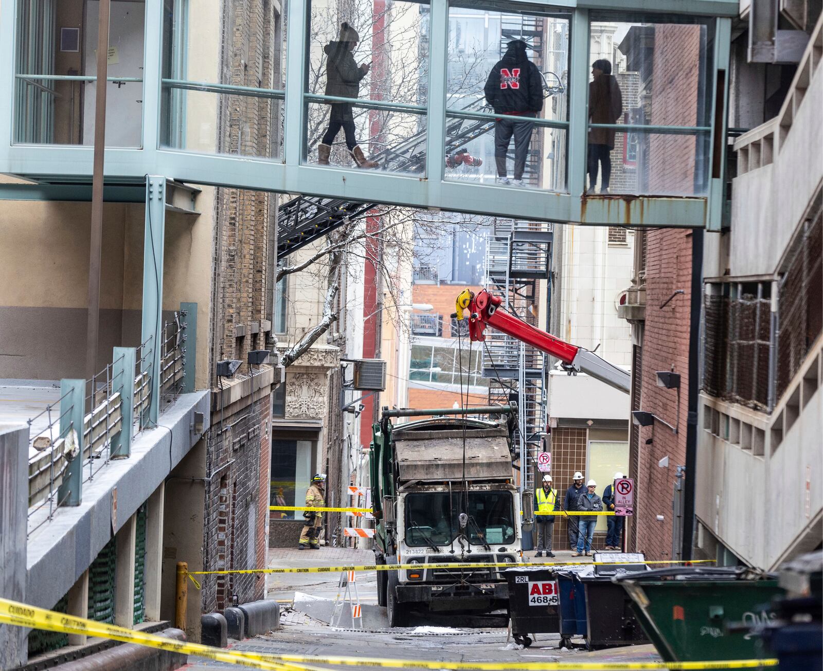 People watch from a skywalk as workers use a crane to lift a garbage truck that got stuck in a sinkhole in downtown Omaha, Neb., Thursday, Jan. 2, 2025. (Chris Machian/Omaha World-Herald via AP)