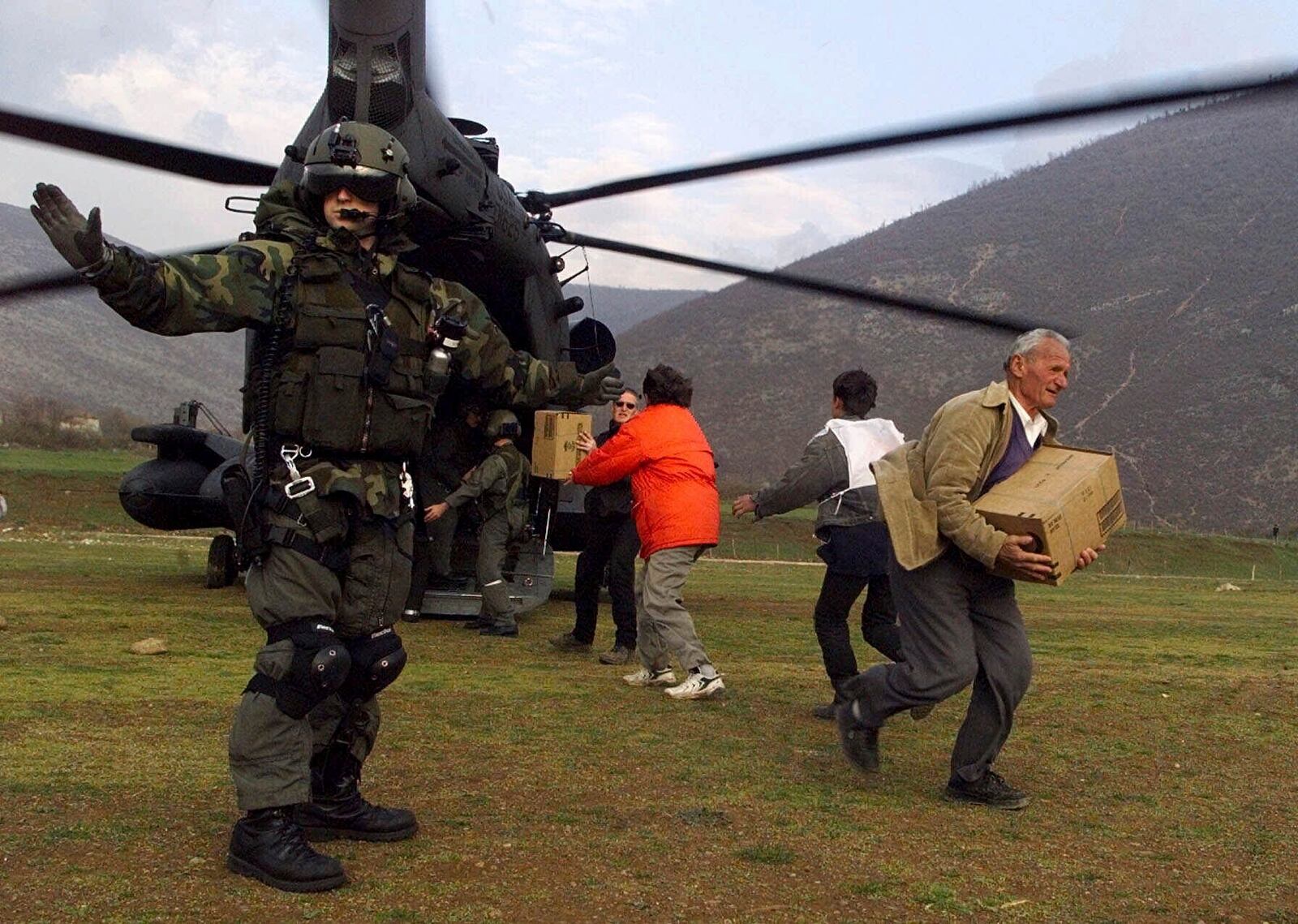 FILE - An unidentified U.S. soldier stands guard as Albanian aid workers unload boxes of U.S. "Humanitarian Daily Rations" from a transport helicopter in Kukes, Albania at the Albania-Kosovo border April 4, 1999. (AP Photo/Michel Euler, File)