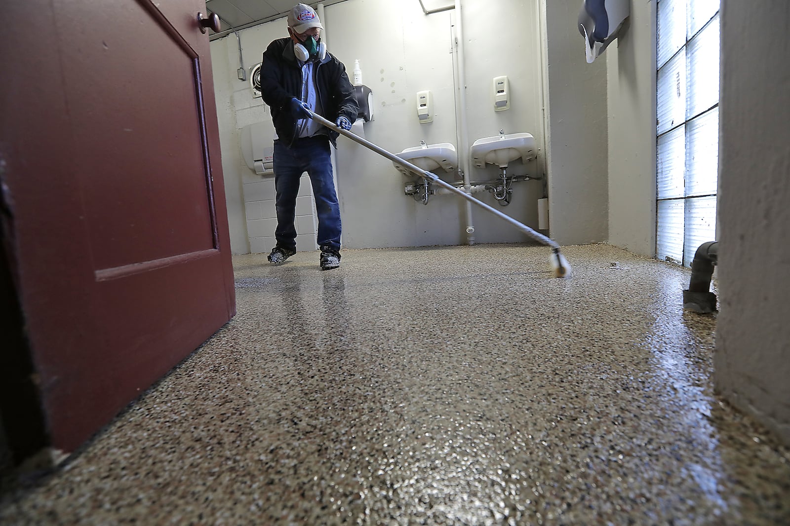 A worker puts down a new FLEXMAR Polyaspartic floor coating in one of the updated restrooms at the Clark County Fairgrounds. BILL LACKEY/STAFF