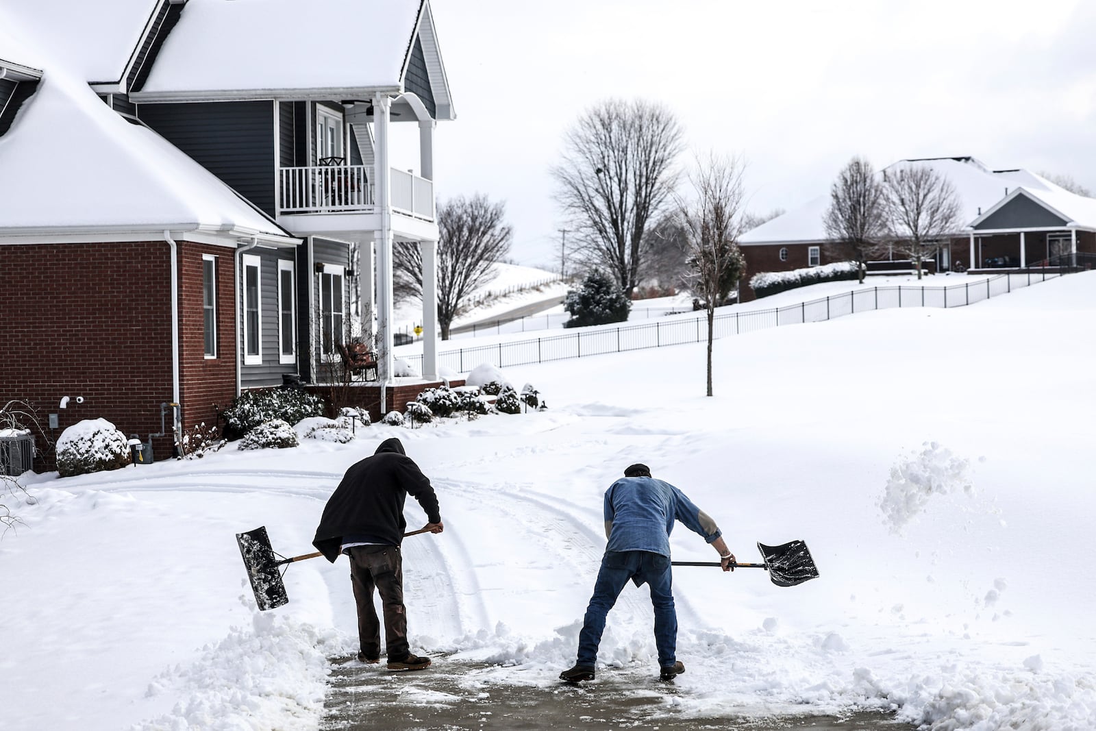 Joe Huff, left, and Kenny Braden with "The Yard Barber" work to clear snow from the driveway of a home in The Summit neighborhood, Saturday, Jan. 11, 2025, in Owensboro, Ky. (Greg Eans/The Messenger-Inquirer via AP)