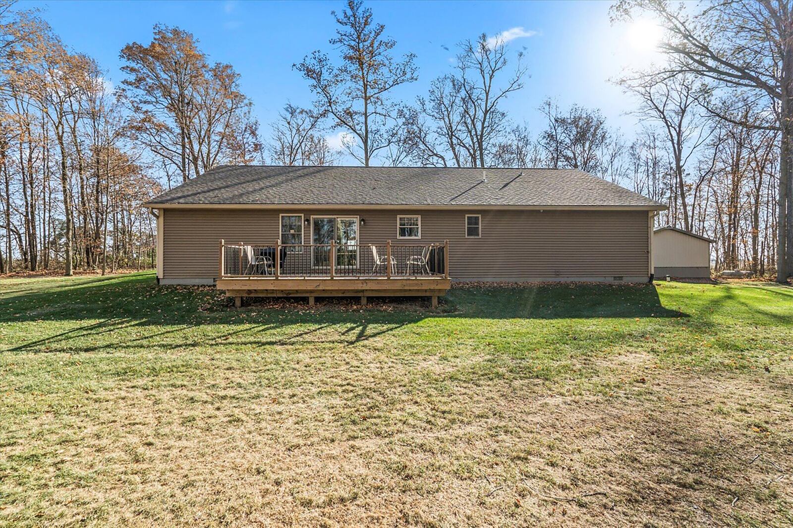 The rear of the home has a wood deck and railings and has a view of the wooded back yard.