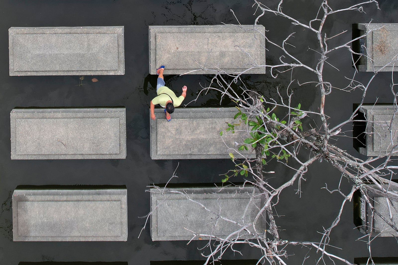 A man walks on top of submerged tombs at flood-prone Holy Spirit Memorial Park in Masantol, Pampanga province, Philippines after heavy rains from recent tropical storm Trami caused water levels to become higher than usual ahead of All Saints Day, Thursday Oct. 31, 2024. (AP Photo/Aaron Favila)